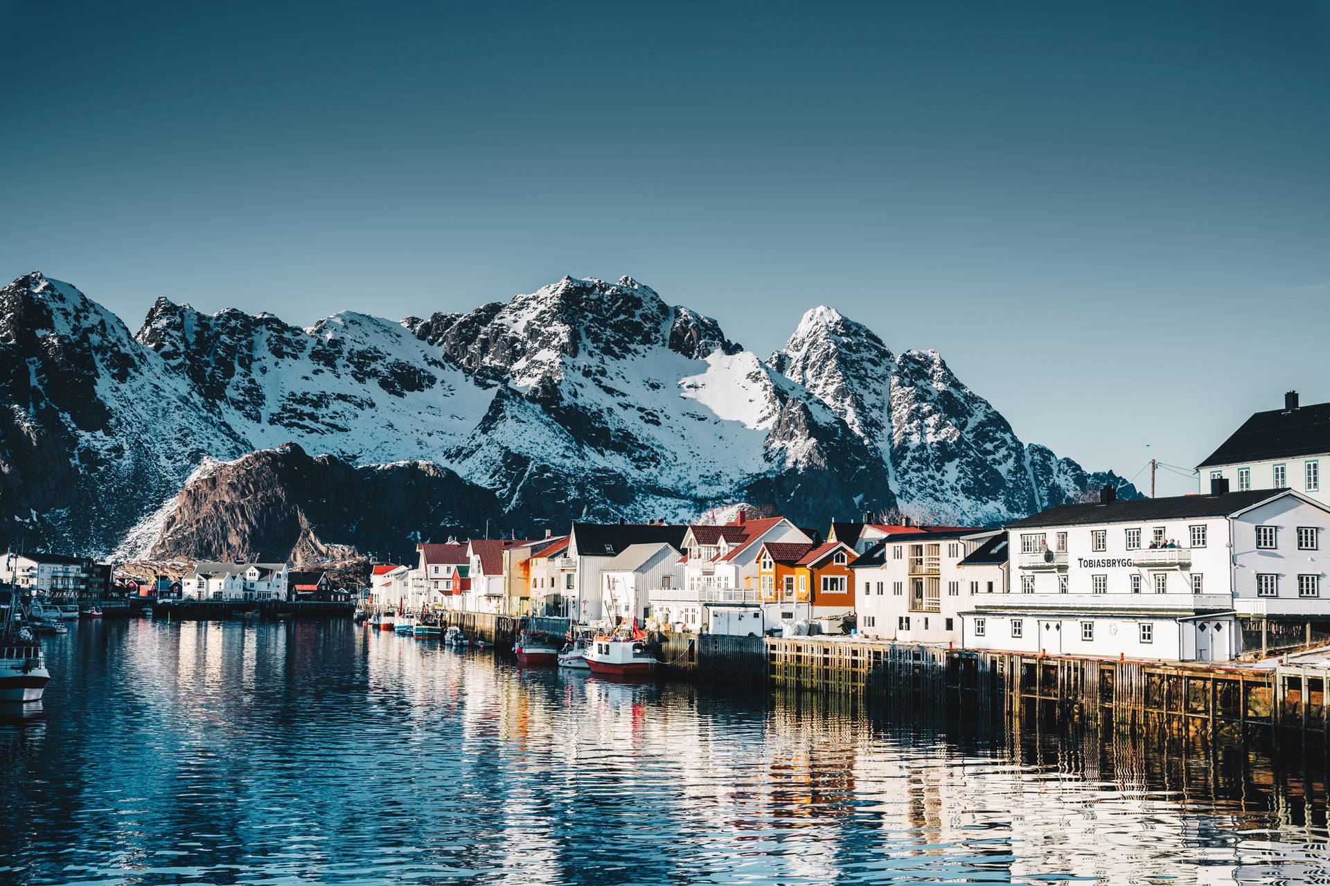 Kolorowe domy w Henningsvær, Norwegia, na tle ośnieżonych gór.