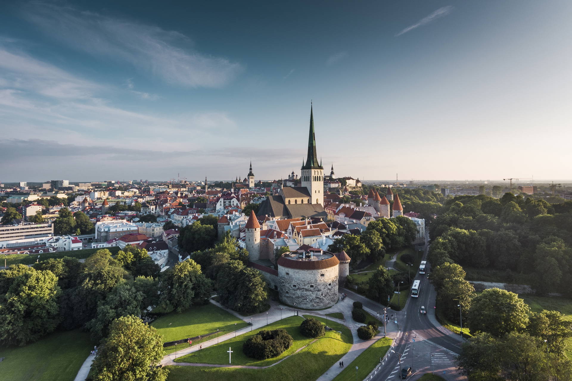Widok z lotu ptaka na Stare Miasto w Tallinnie. W centrum widać Kościół św. Olafa, a wokół mury obronne z basztami i park.