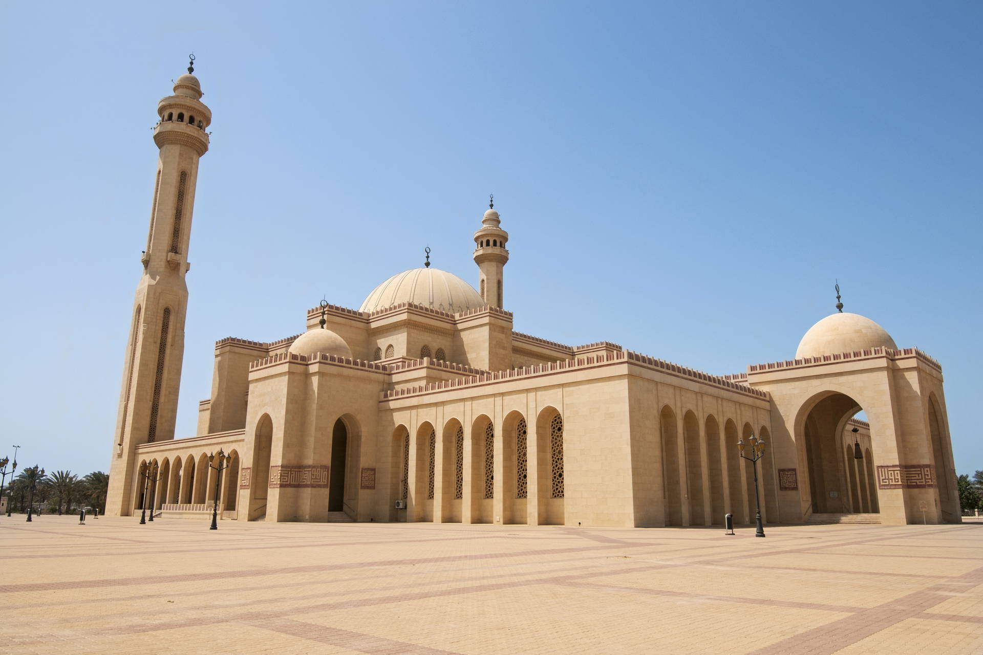 Kopuły i minarety Wielkiego Meczetu Al-Fateh w Bahrajnie na tle błękitnego nieba.