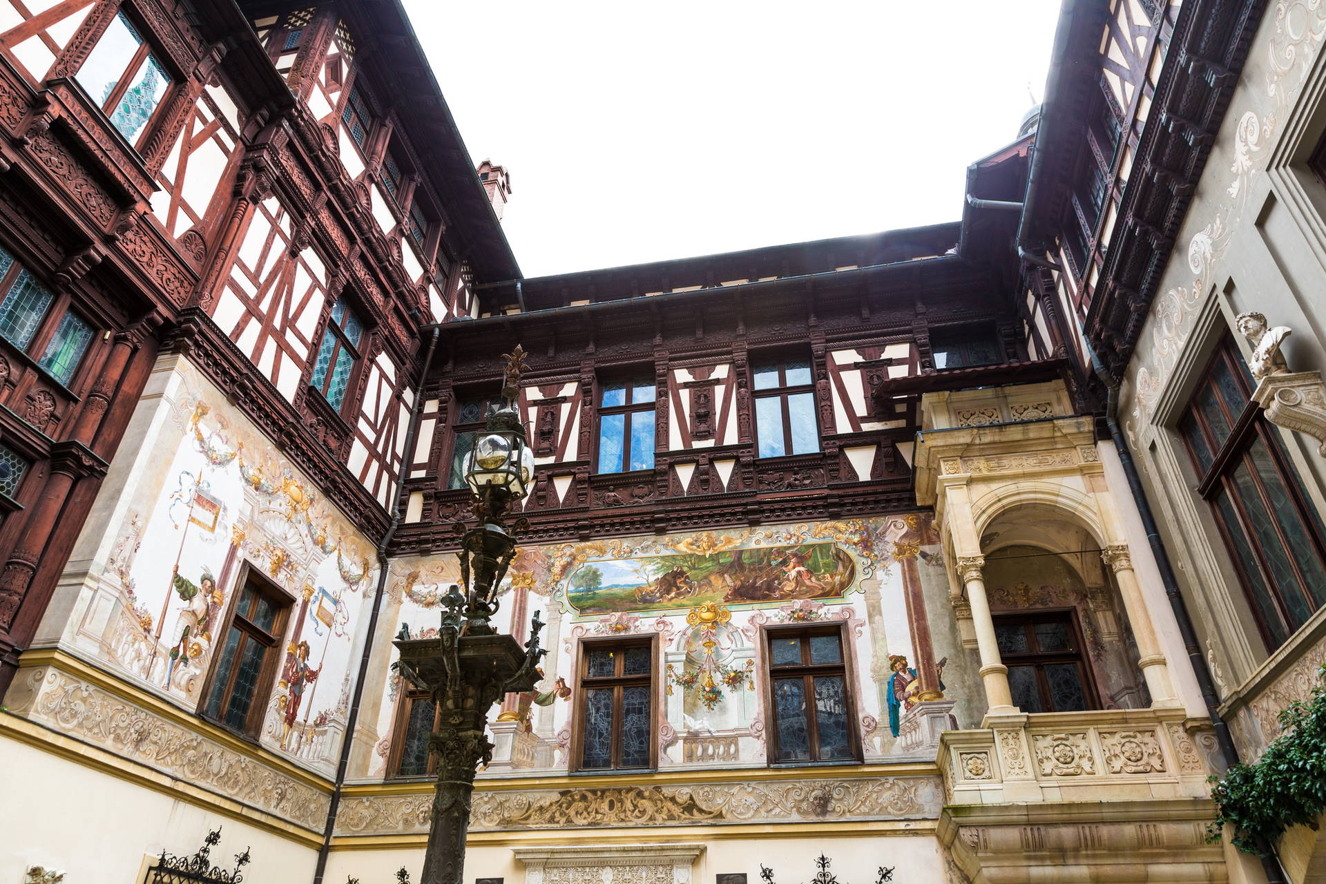 Dziedziniec Zamku Peleș z dekoracyjnymi malowidłami i architekturą neorenesansową.