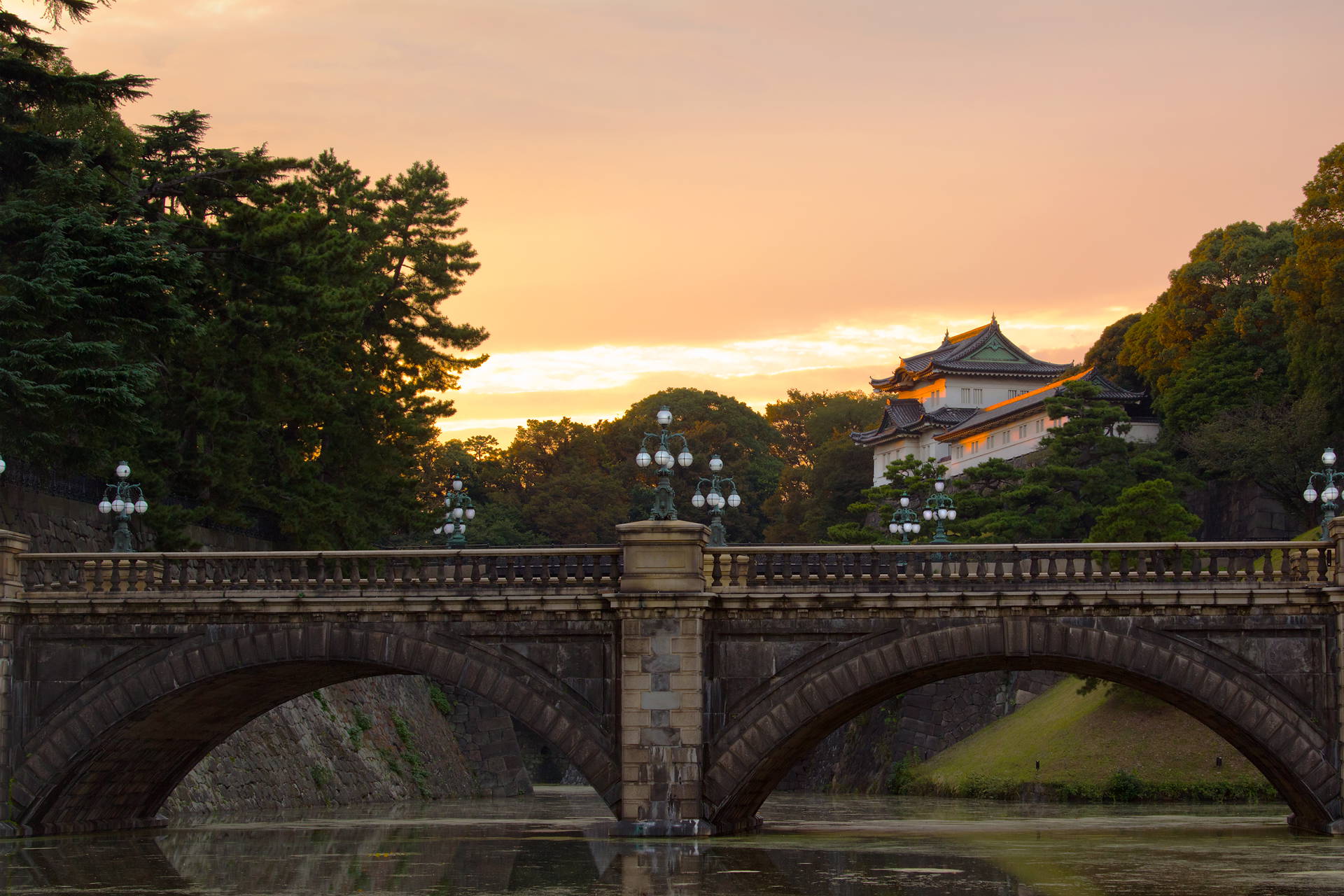 Kamienny most z latarniami na tle Pałacu Cesarskiego w Tokio.