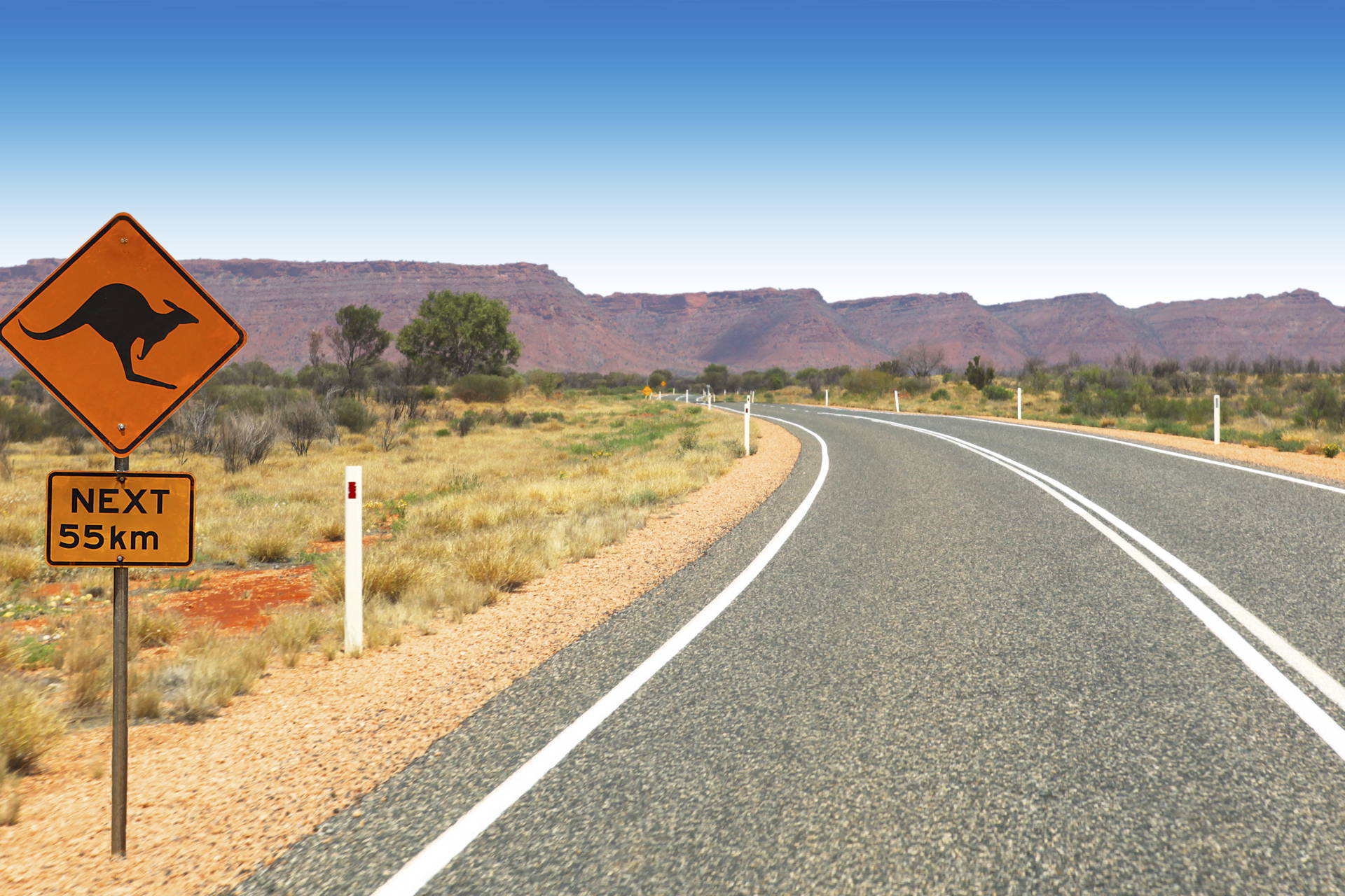 Długa, australijska droga ze znakiem ostrzegającym przed kangurami.