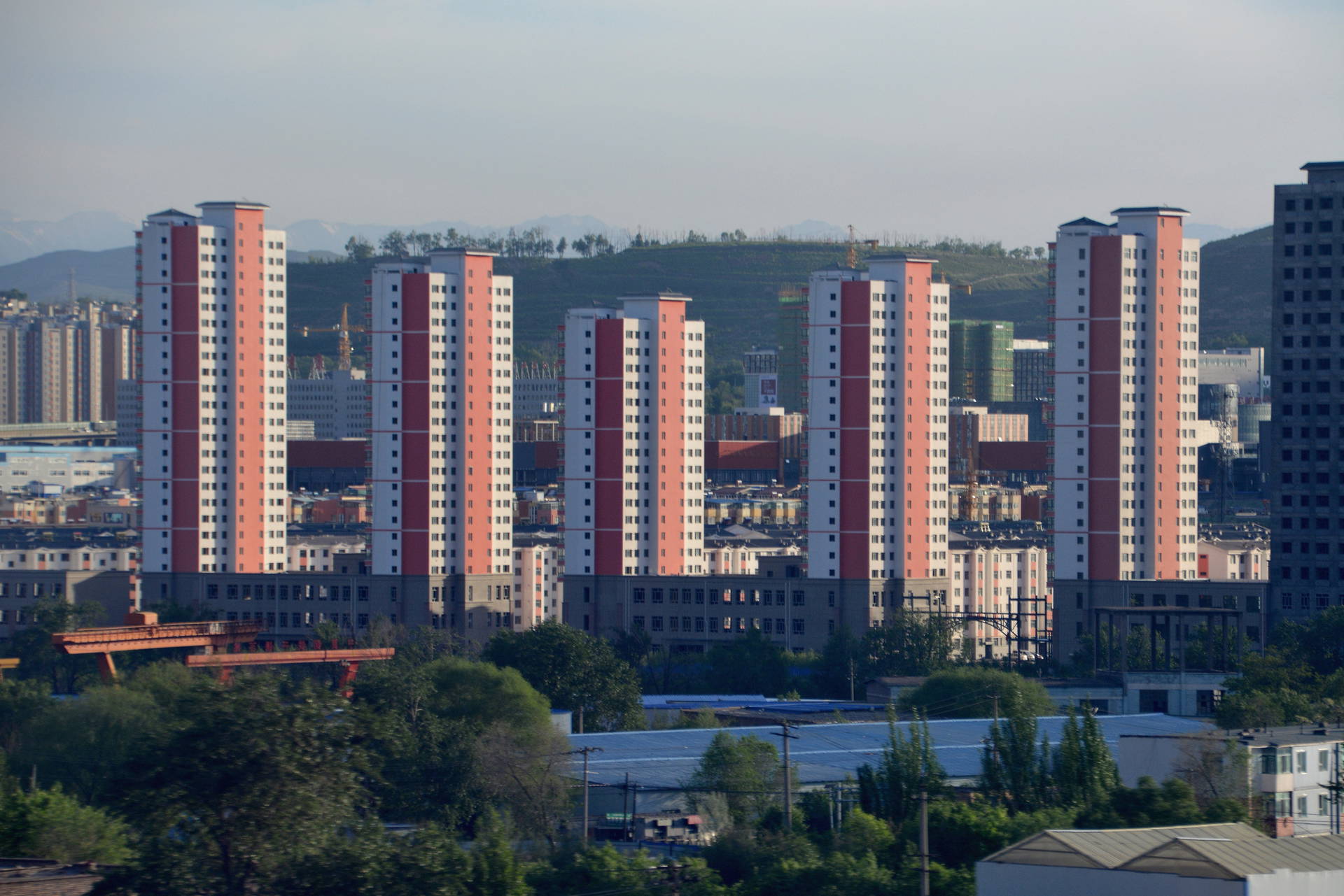 Widok na miasto z wysokimi budynkami i drzewami w tle.