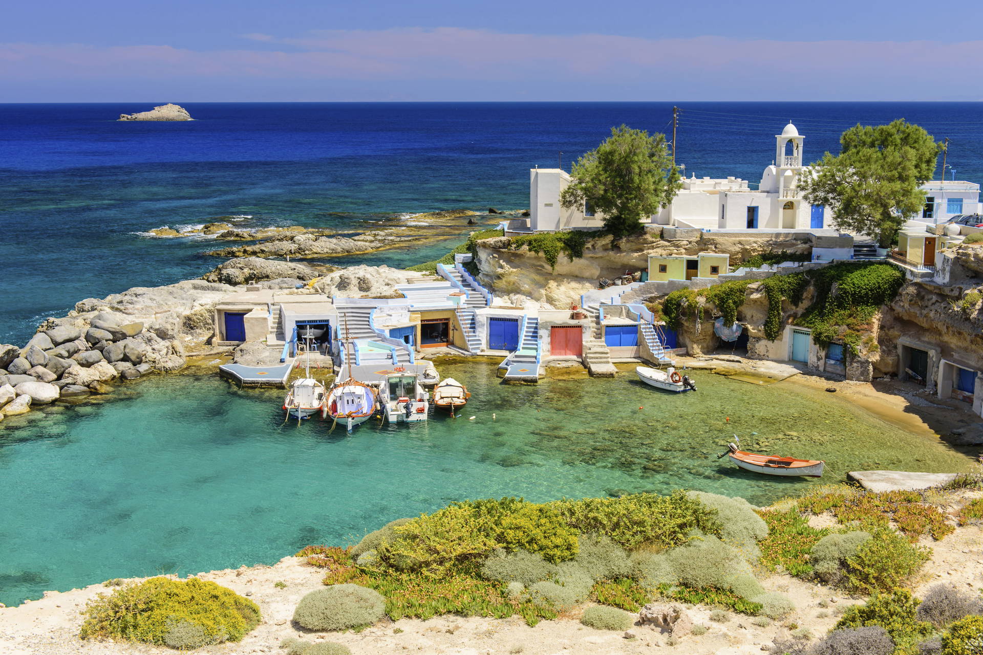 Port Mandraki w Grecji z łodziami i białą zabudową.