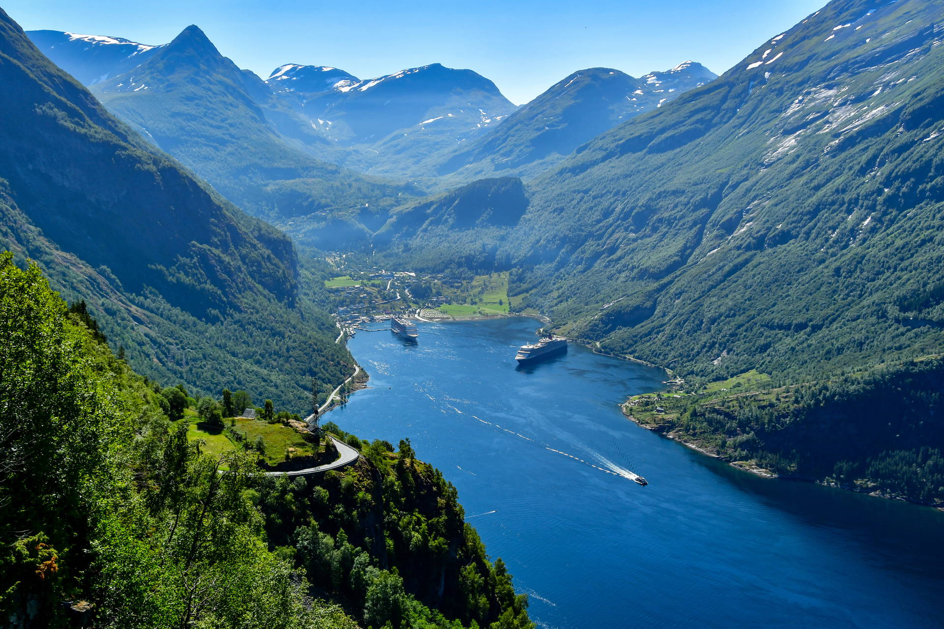 Geirangerfjord w Norwegii z lotu ptaka. Widoczne fiord, góry, dwa statki wycieczkowe i łódź motorowa.
