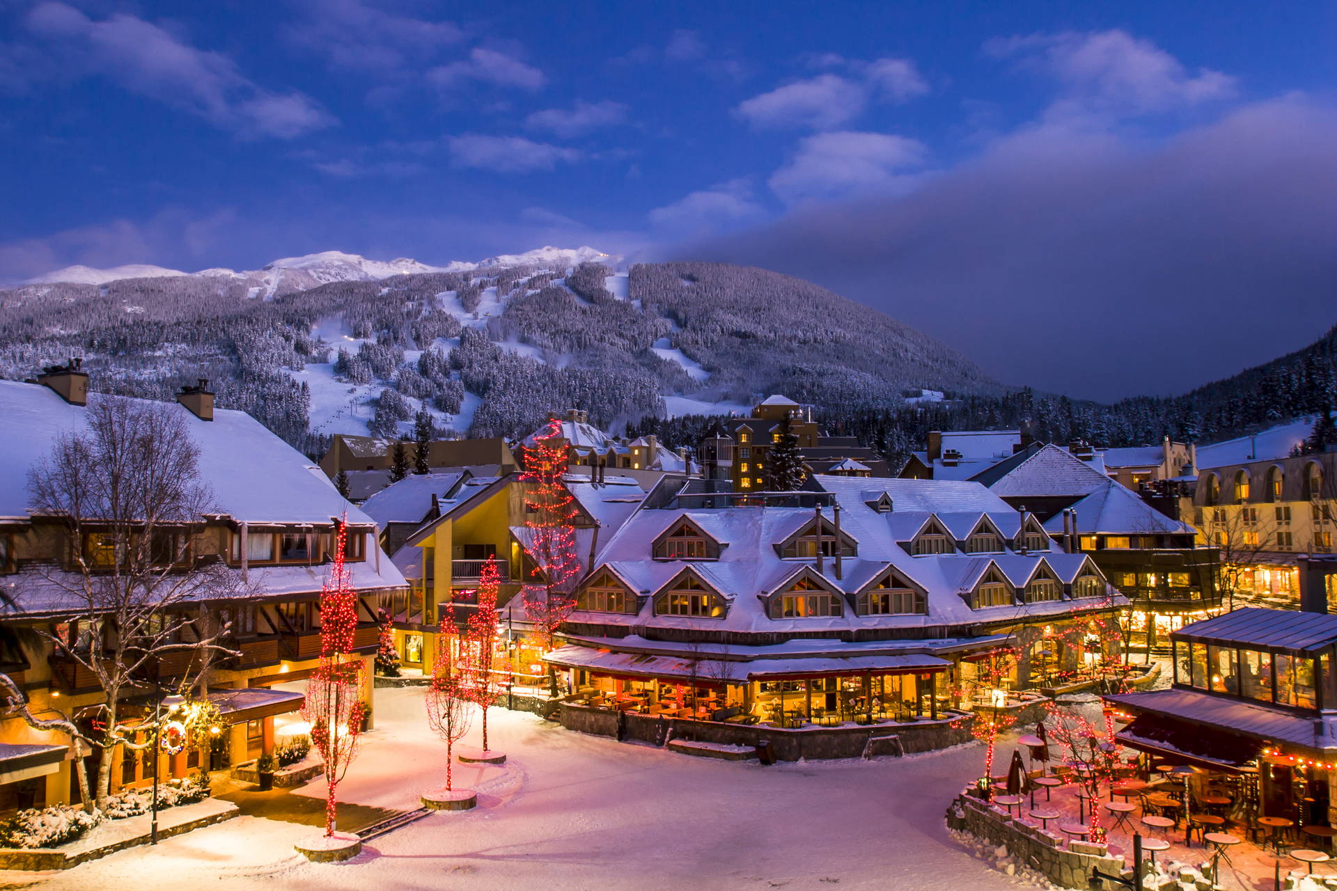 Zimowy krajobraz nocnego, górskiego miasteczka. Budynki są pokryte śniegiem.