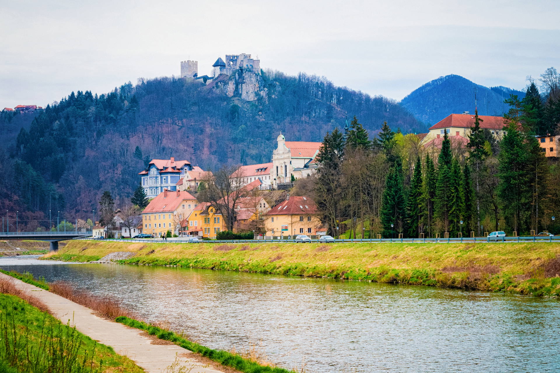 Krajobraz miejski z rzeką i zamkiem Celje w tle.