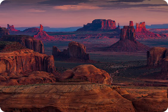 Monument Valley z charakterystycznymi czerwonymi formacjami skalnymi o zachodzie słońca.