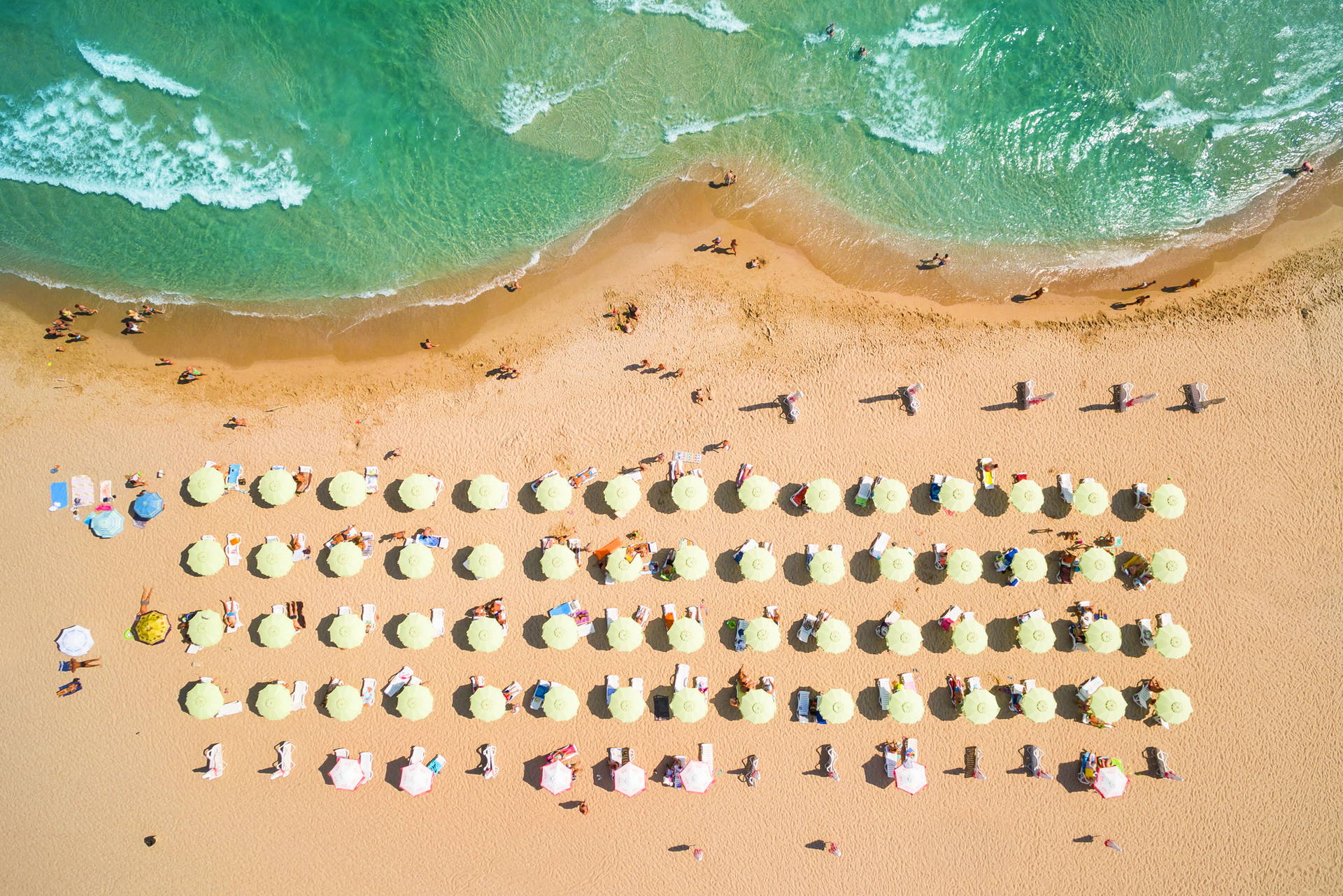 Plaża z parasolami i wypoczywającymi ludźmi, widok z góry.