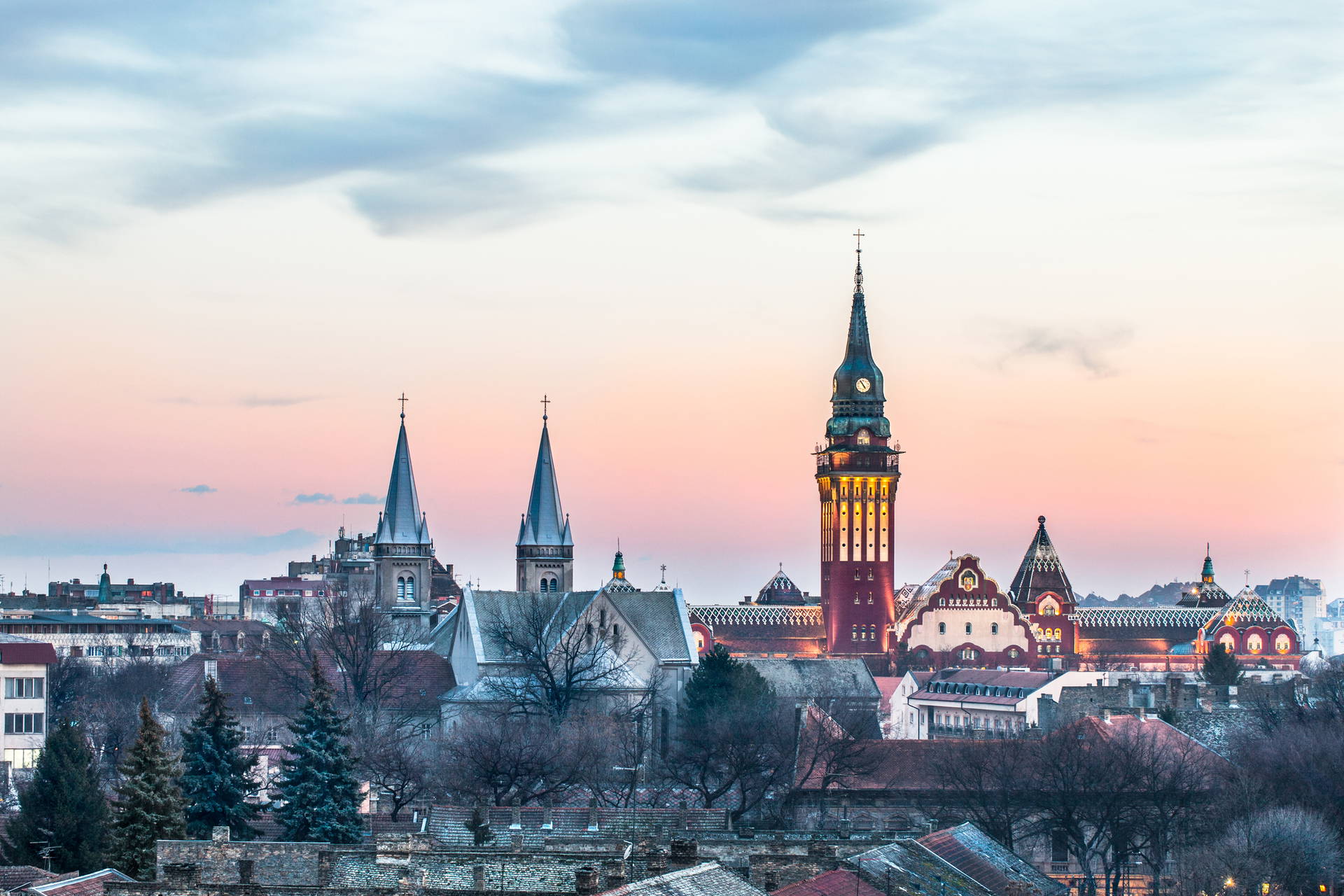 Panorama Suboticy z wieżami kościołów i ratuszem na tle nieba.