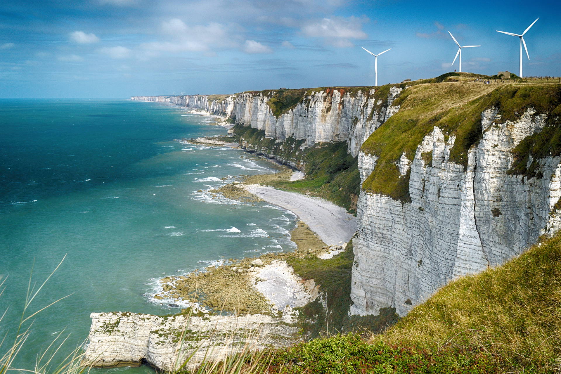 Klify Étretat, morze i turbiny wiatrowe w krajobrazie.
