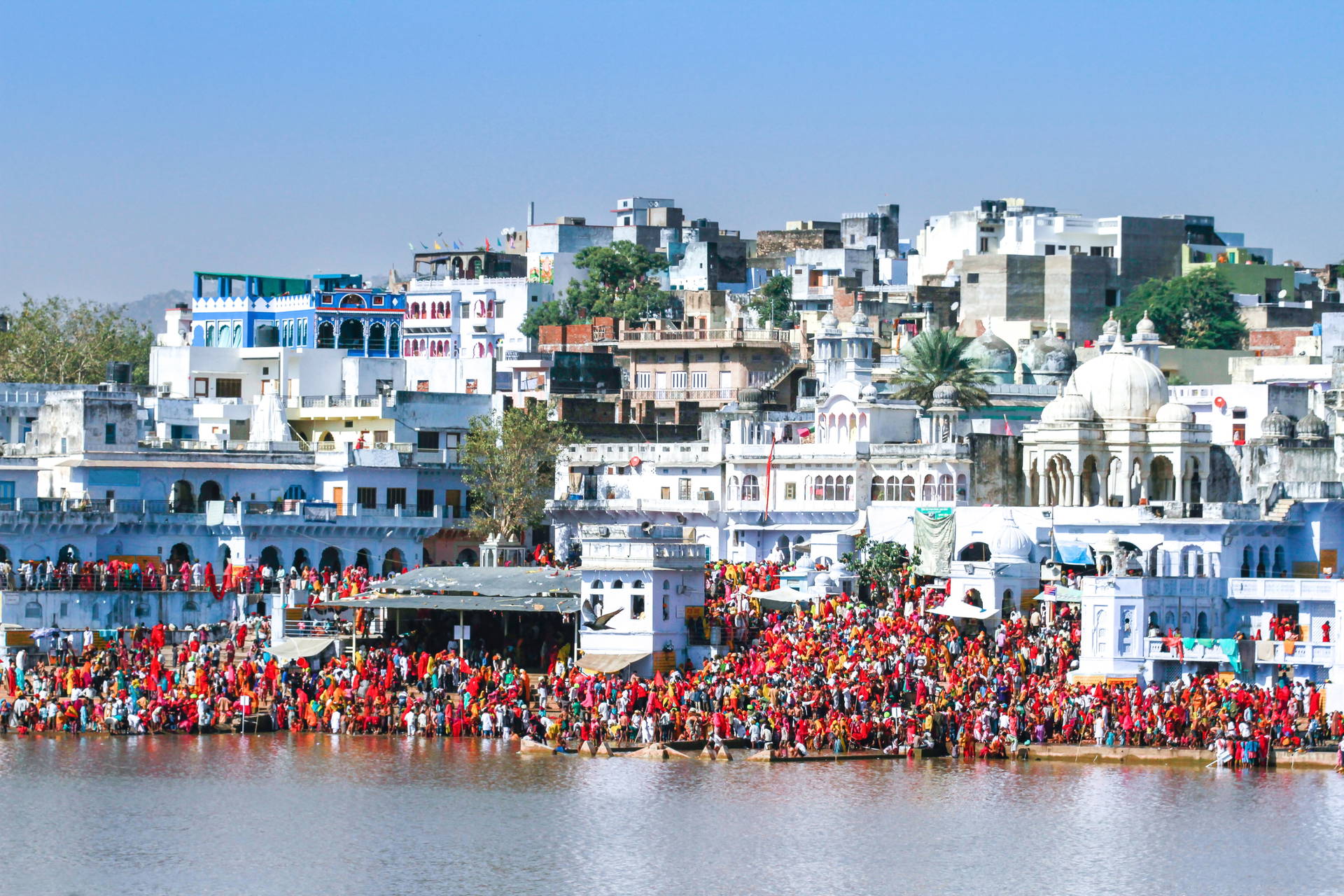 Widok na miasto Pushkar w Indiach i tłumy ludzi nad jeziorem.