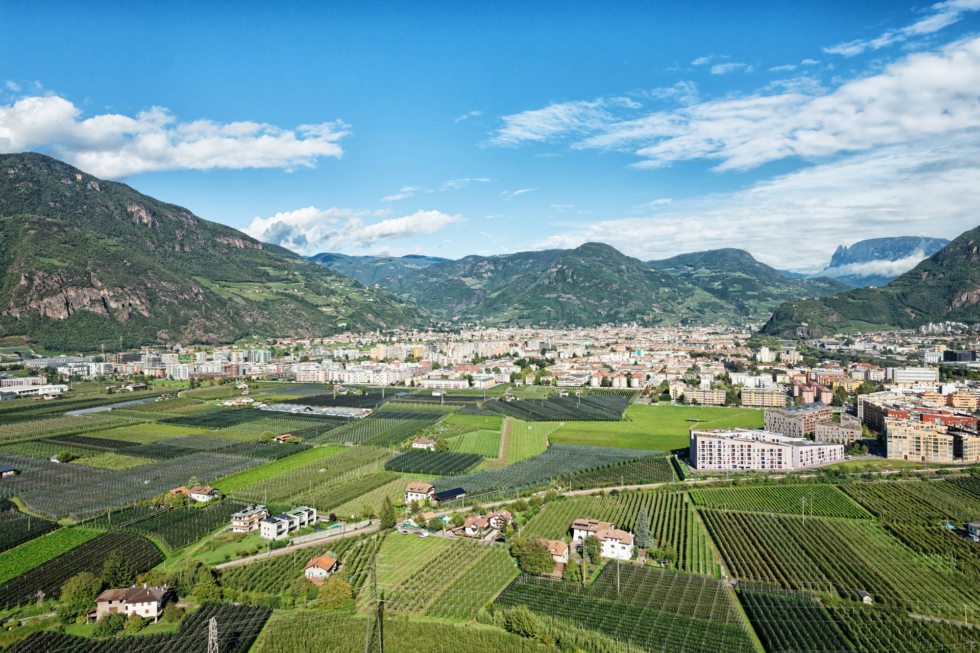 Panorama Bolzano: miasto otoczone górami i zielonymi polami.