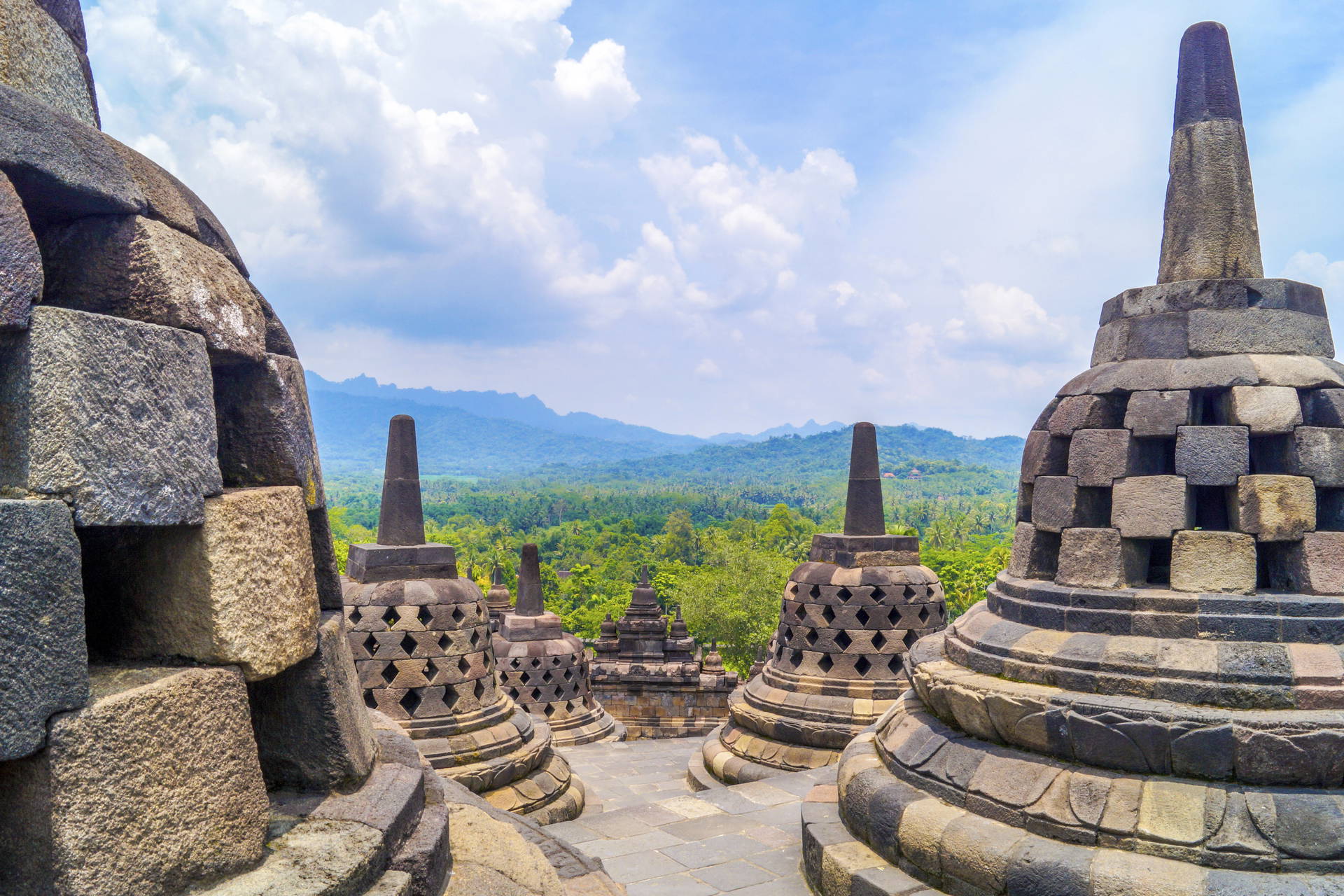 Stupa w Borobudur na tle zalesionych wzgórz.