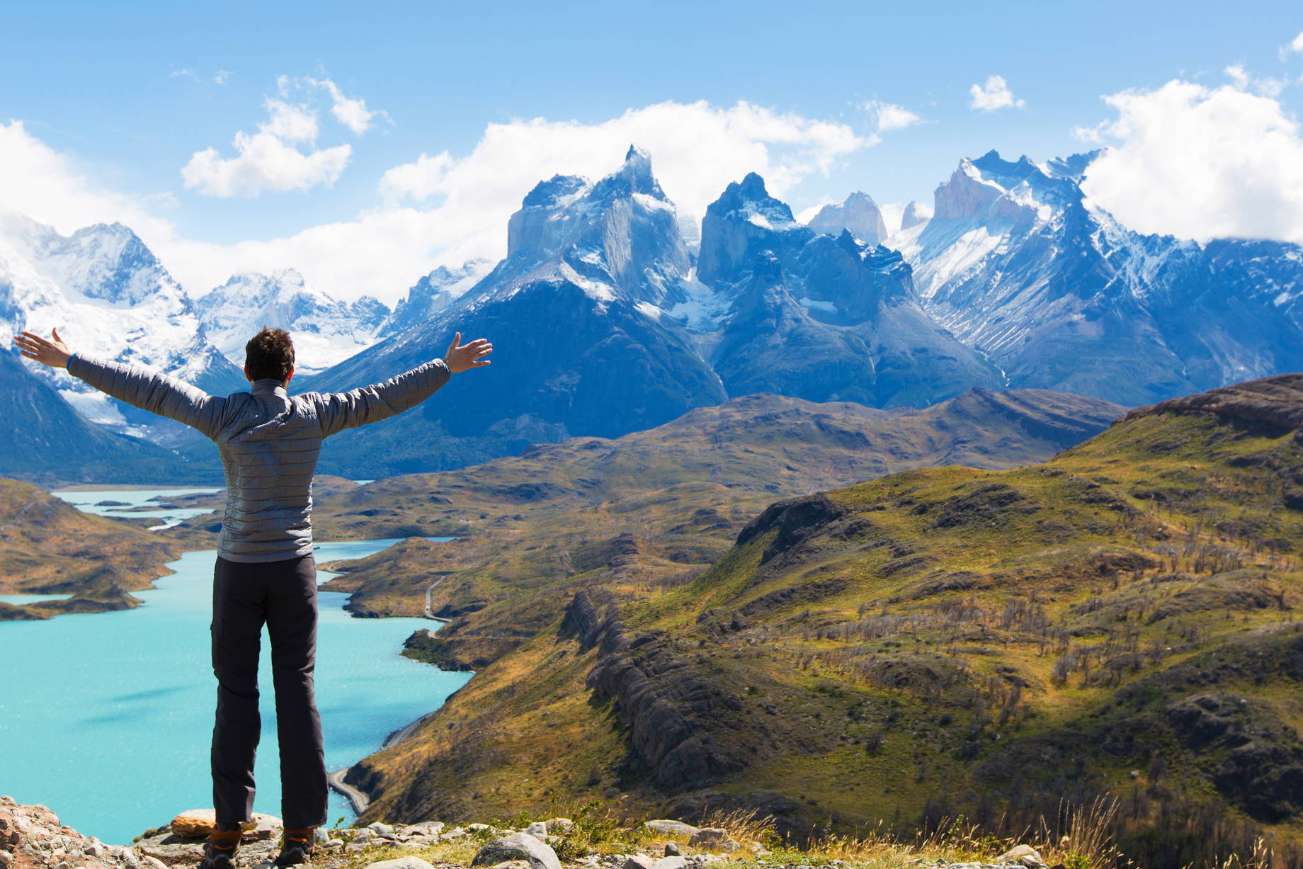 Mężczyzna z rozłożonymi ramionami podziwia widok na góry w Parku Narodowym Torres del Paine.