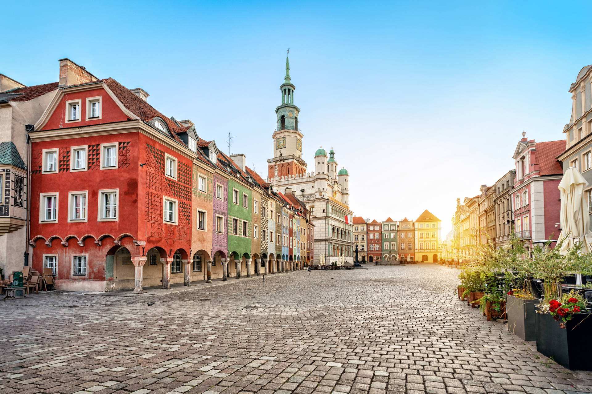 Rynek w Poznaniu z renesansowym ratuszem i kolorowymi kamienicami w tle.