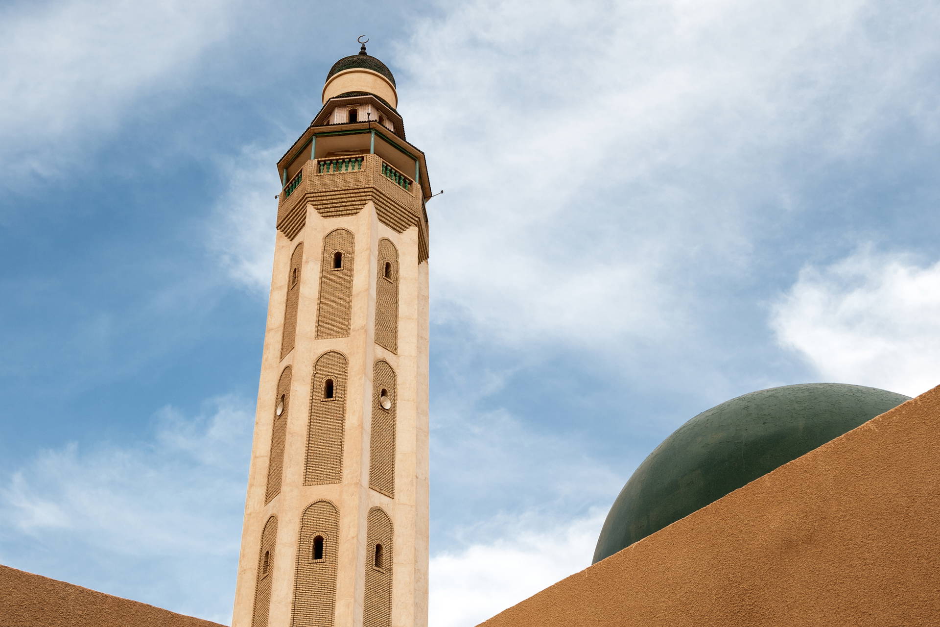 Minaret meczetu z kopułą na tle nieba.