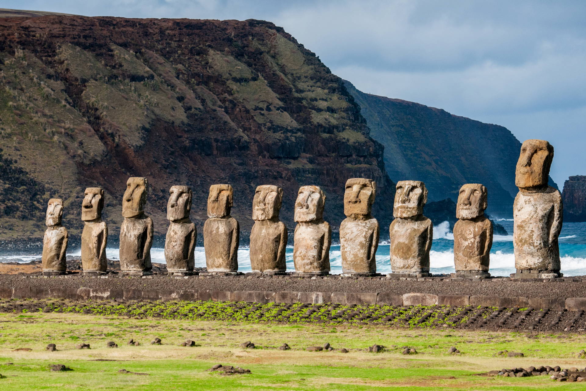Kamienne posągi Moai na tle zbocza góry i oceanu, Wyspa Wielkanocna.
