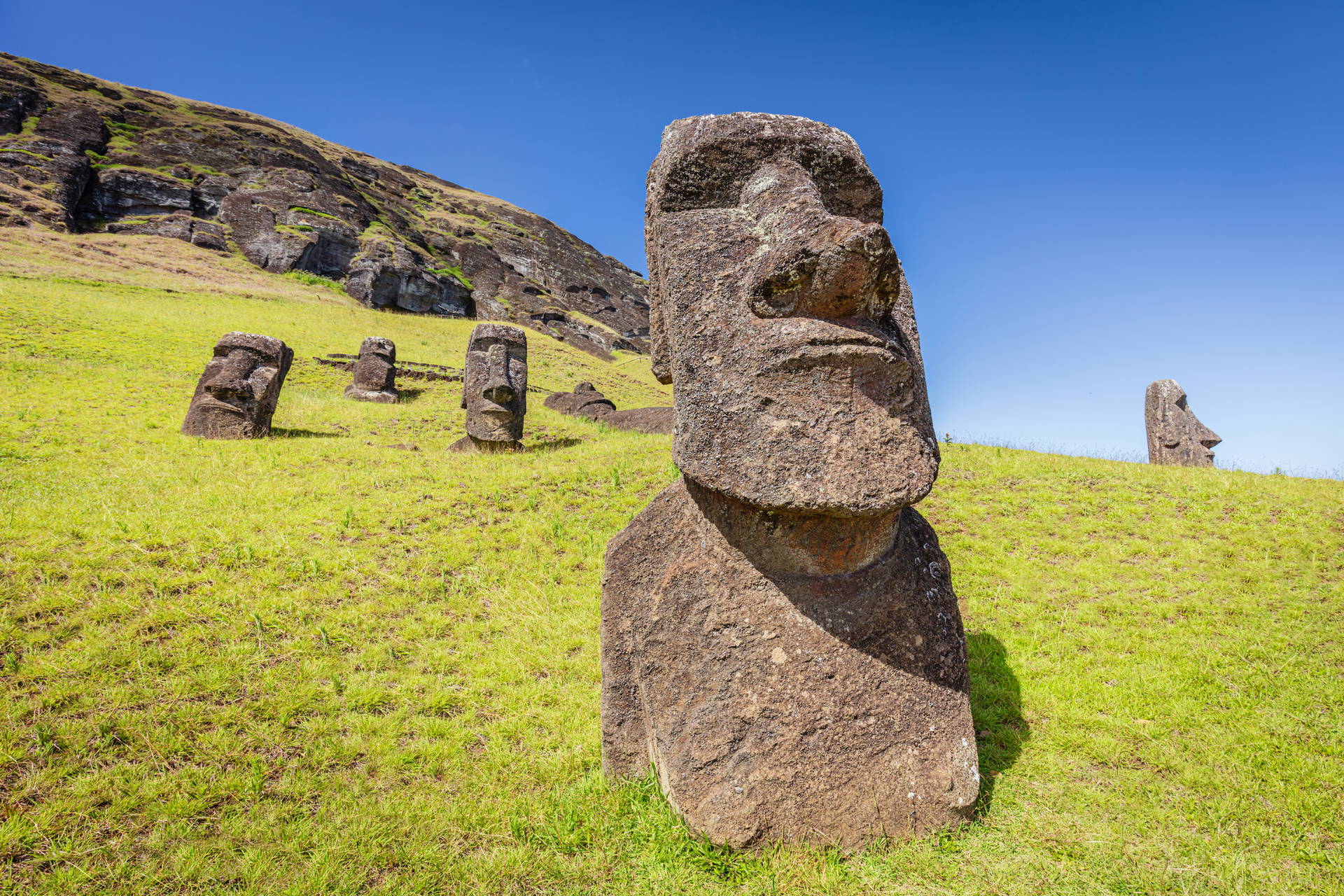 Posągi Moai na tle wzgórza i nieba, Wyspa Wielkanocna.