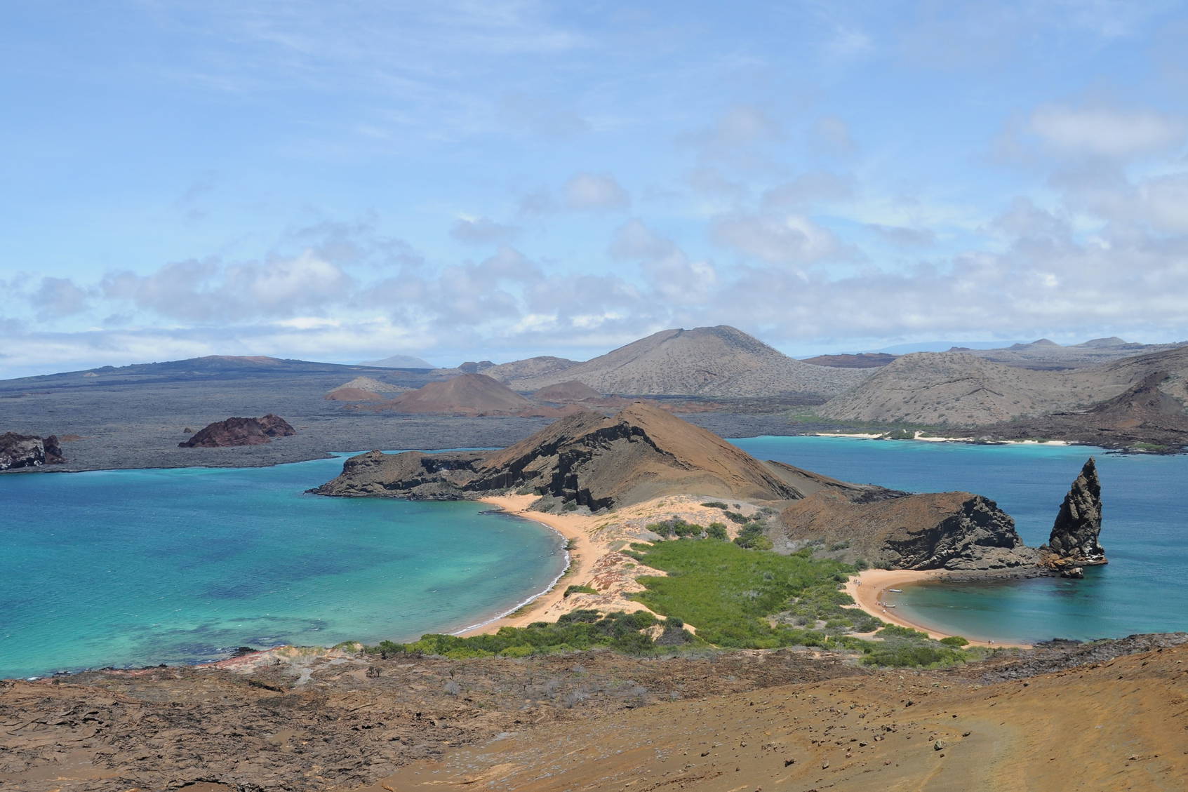 Krajobraz wyspy Galapagos: turkusowa woda i wulkaniczne formacje skalne.