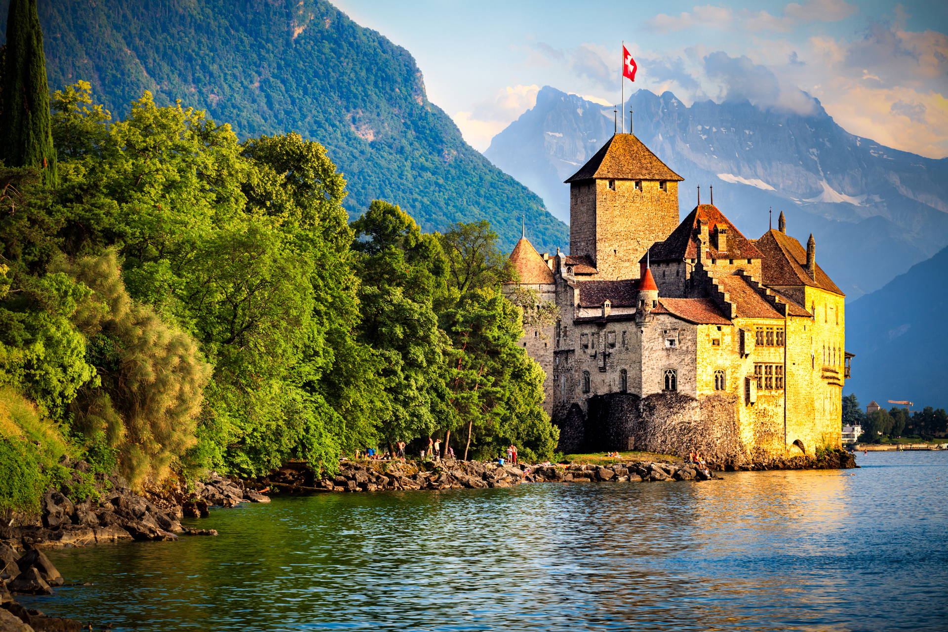 Zamek Chillon w Szwajcarii położony nad jeziorem, w otoczeniu gór.