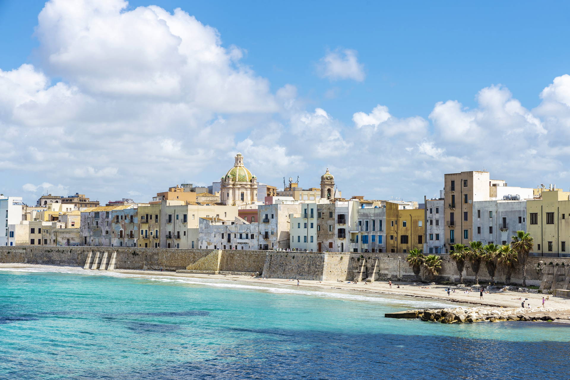 Krajobraz Trapani na Sycylii: morze, plaża i zabudowania w tle.