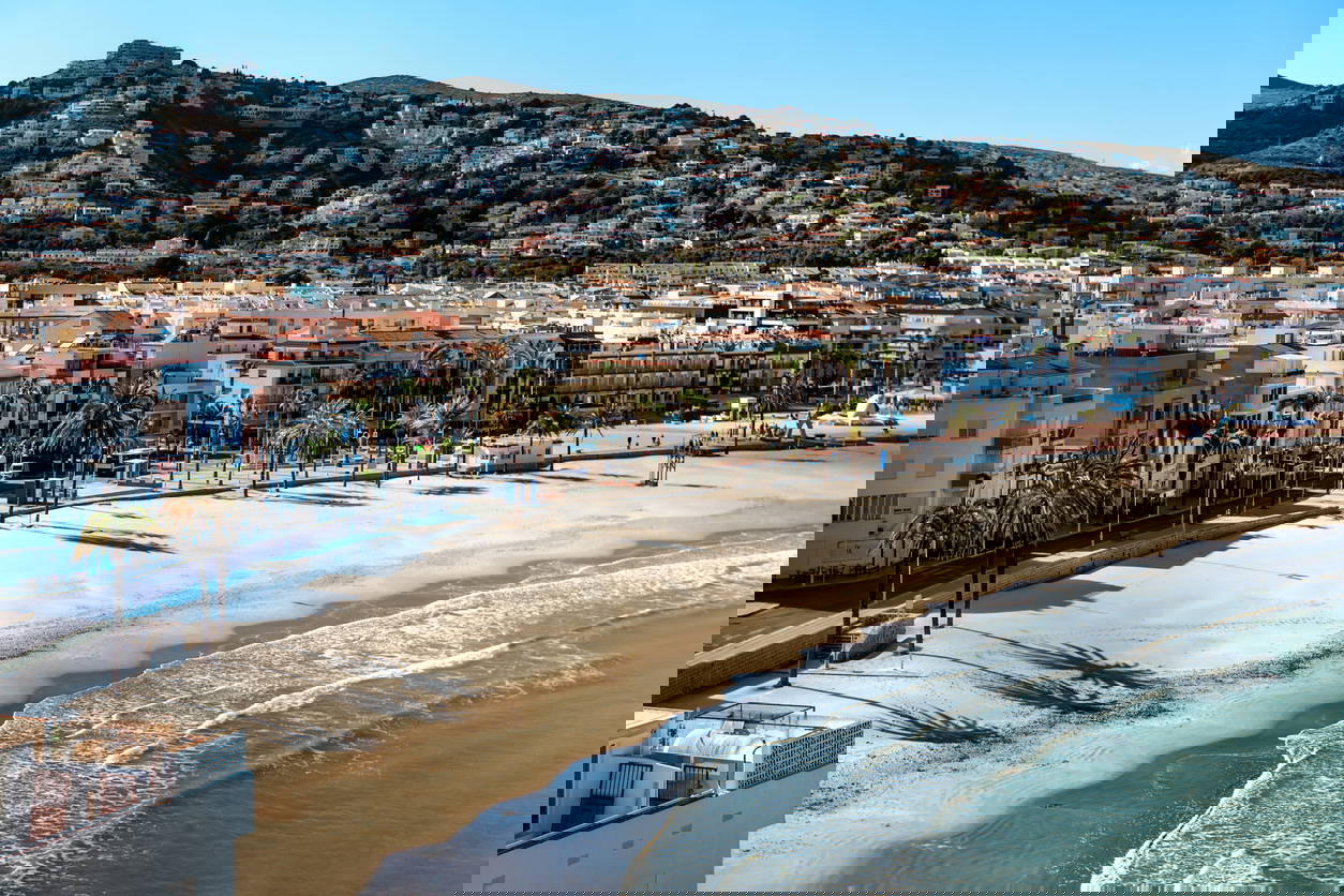 Widok na miasto z plażą i zabudowaniami na wzgórzu.