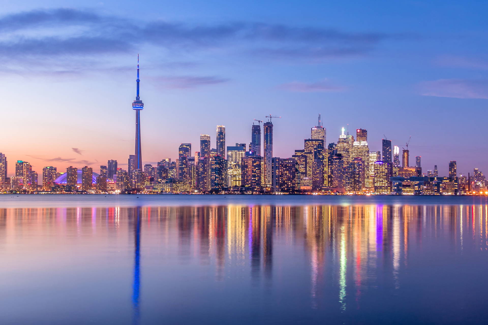 Nocna panorama Toronto. W wodzie odbijają się wieżowce i CN Tower.