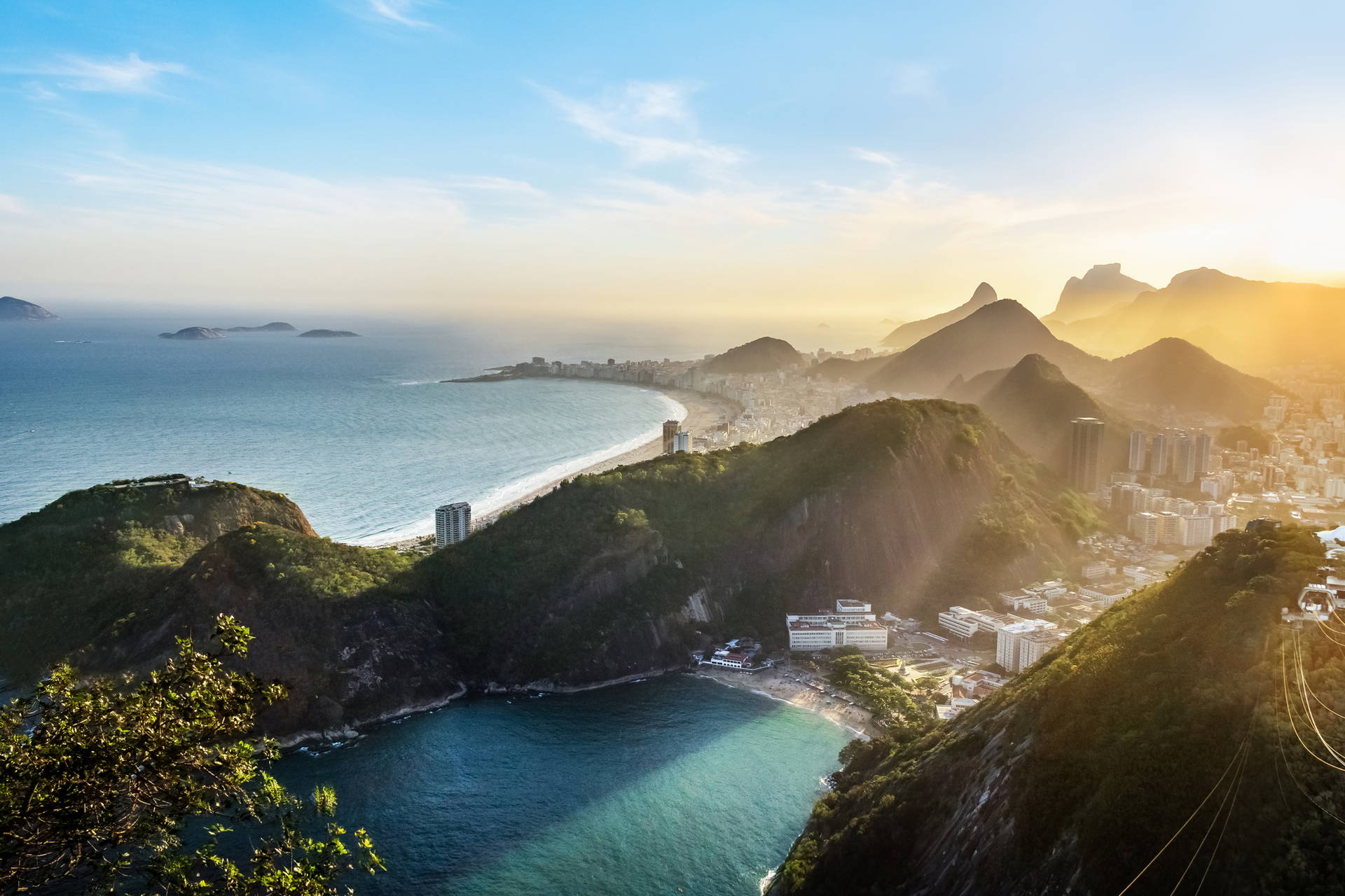 Krajobraz Rio de Janeiro: plaża, góry i budynki skąpane w słońcu.