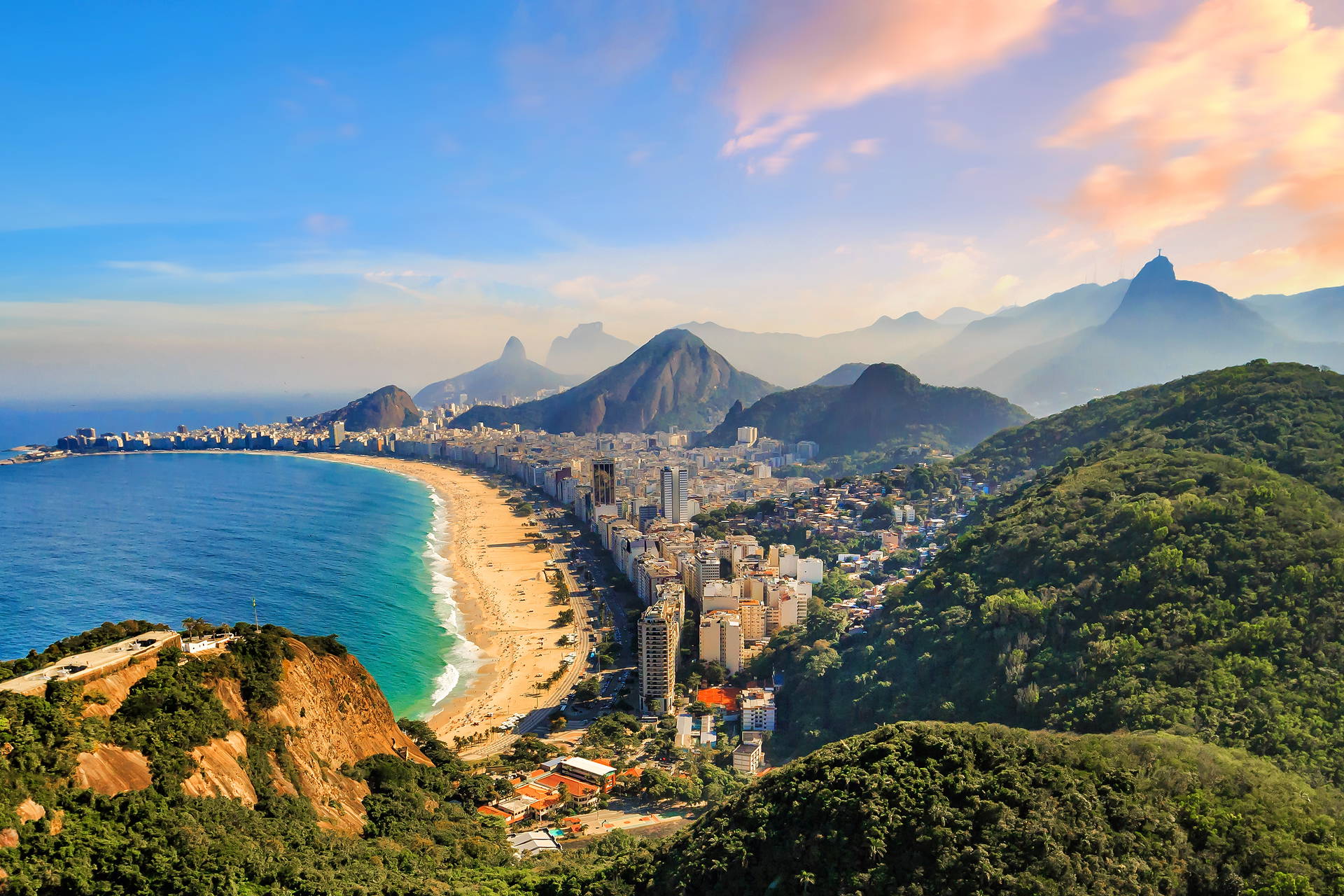 Panorama Rio de Janeiro z widokiem na plażę Copacabana, miasto i pomnik Chrystusa Odkupiciela na wzgórzu w oddali.