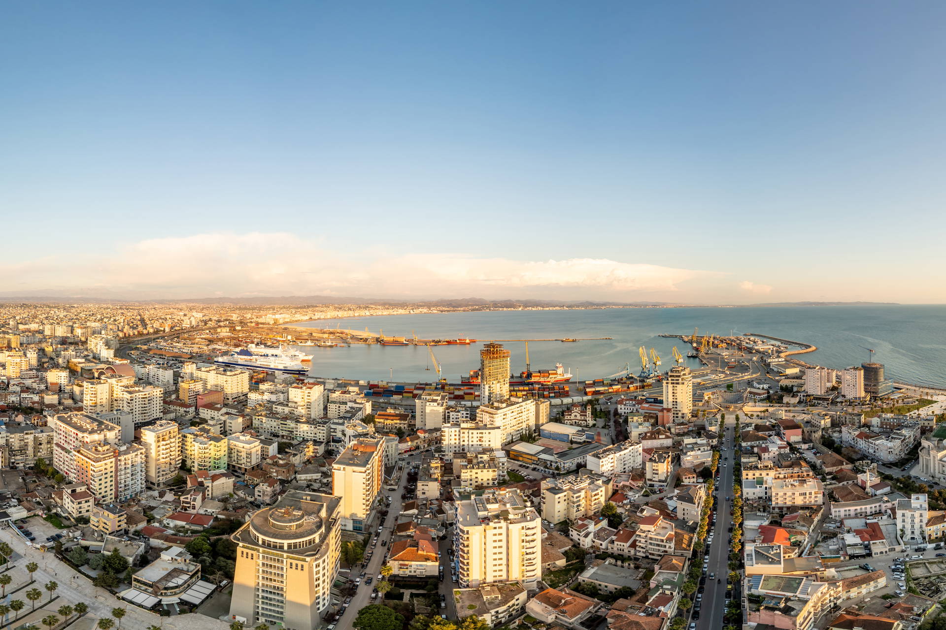 Zachód słońca nad Durrës w Albanii. Widok z góry na panoramę miasta, port i Morze Adriatyckie.