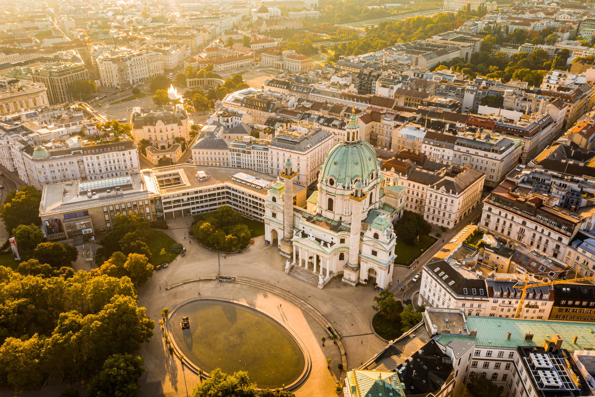 Kościół św. Karola Boromeusza i panorama Wiednia z lotu ptaka w złotym świetle słońca.
