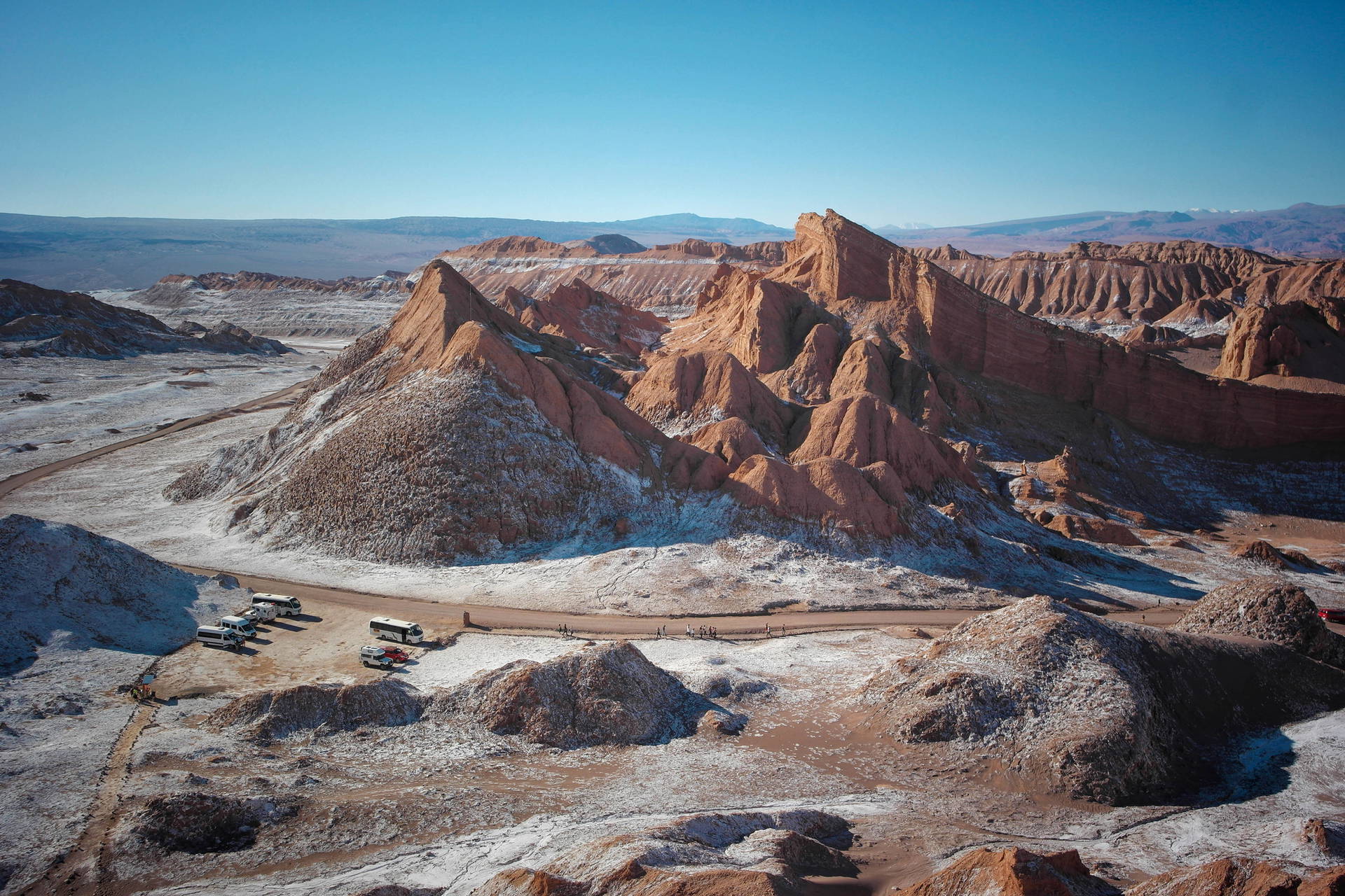 Krajobraz Doliny Księżycowej z formacjami skalnymi, drogą i autokarami.