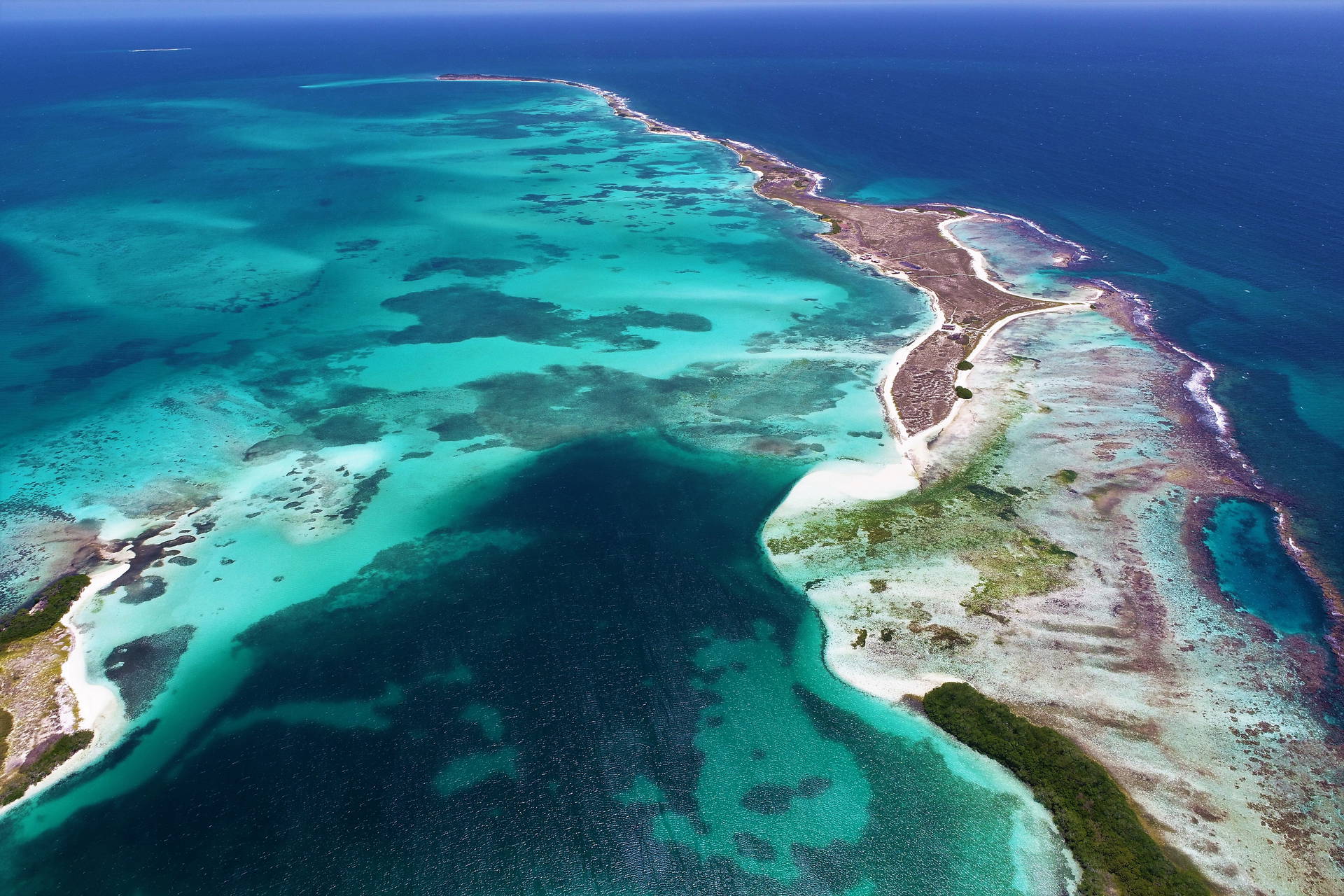Widok z lotu ptaka na tropikalną wyspę otoczoną turkusową wodą.