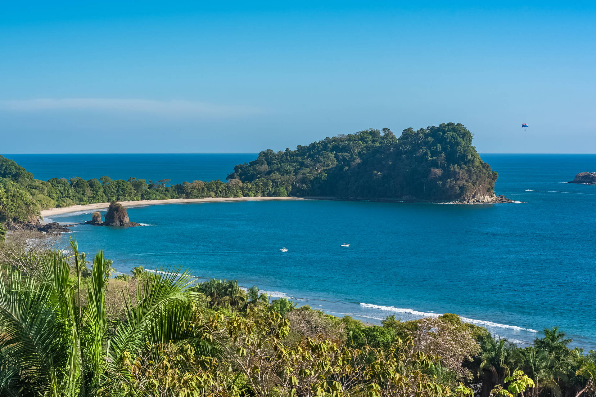 Plaża Manuel Antonio w Kostaryce. Widoczne zielone wzgórza, błękitny ocean i mała wyspa.