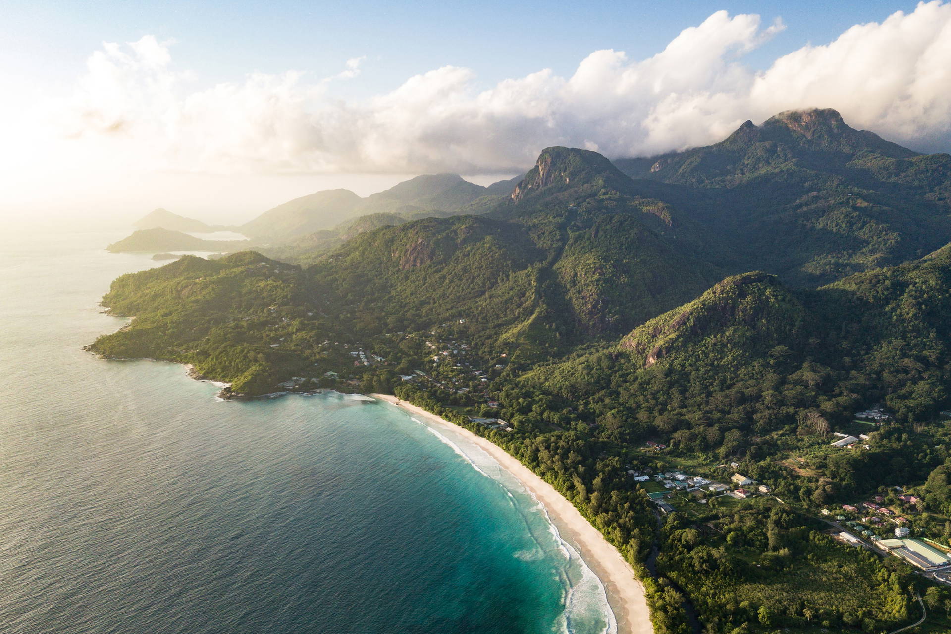Widok z lotu ptaka na plażę u podnóża gór porośniętych lasem.