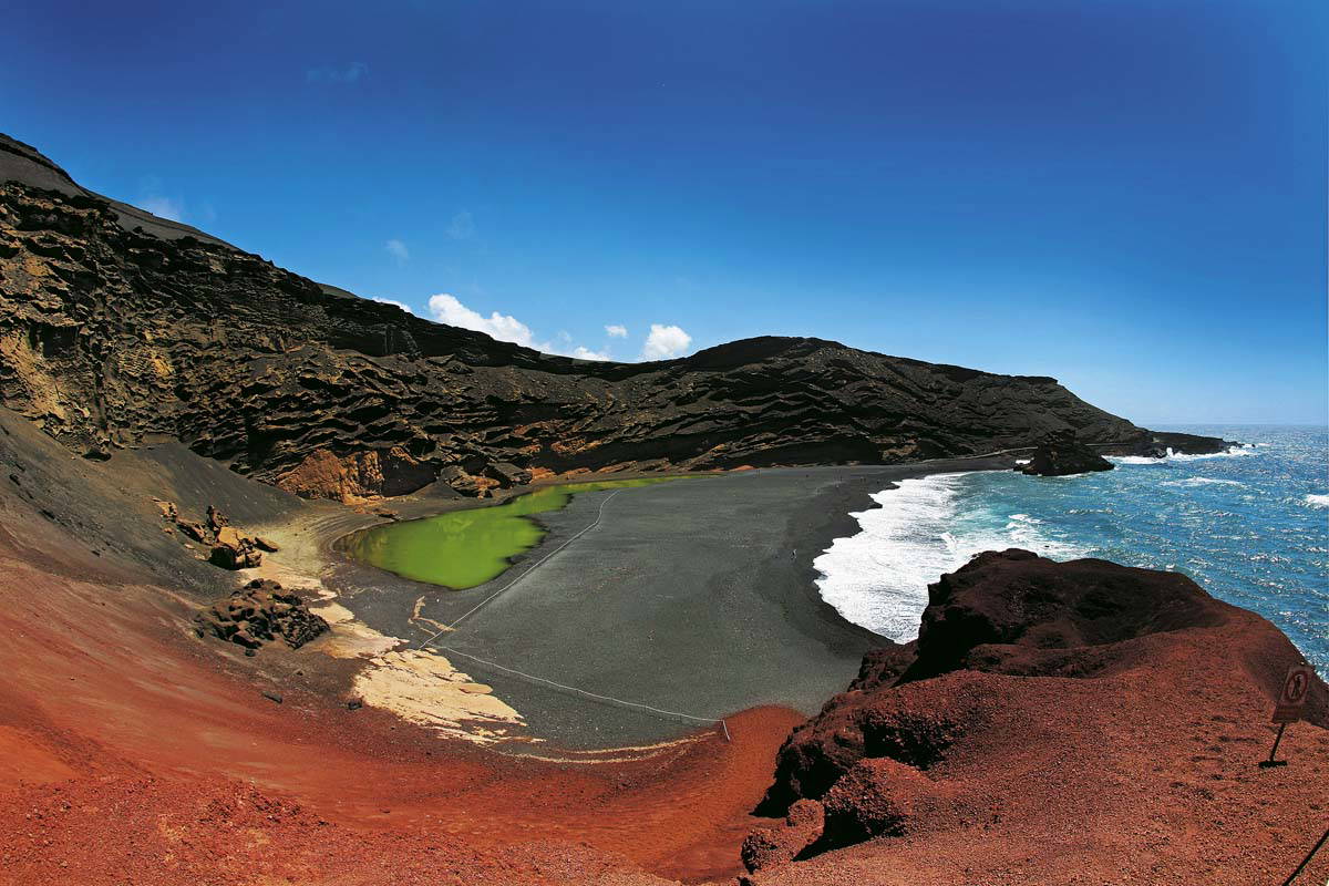Krajobraz El Golfo na Lanzarote z zielonym jeziorkiem, czarną plażą i oceanem.
