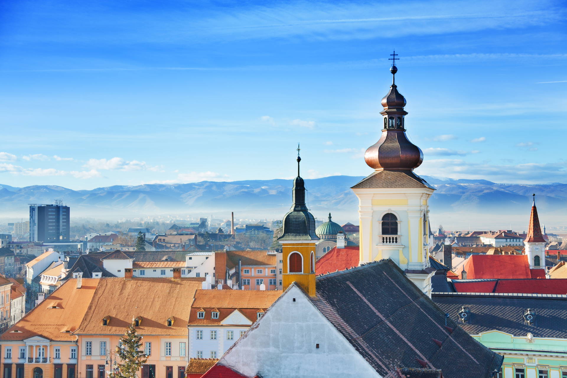 Panorama miasta Sybin z wieżami kościołów na tle gór.