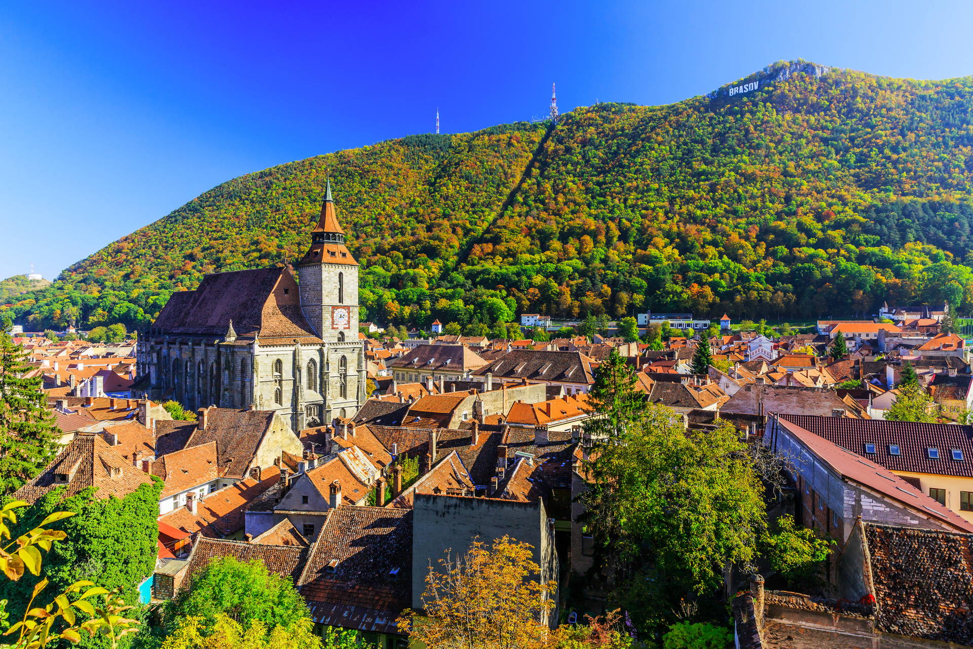 Panorama rumuńskiego miasta Braszów z Czarnym Kościołem i napisem "Brasov" na wzgórzu.