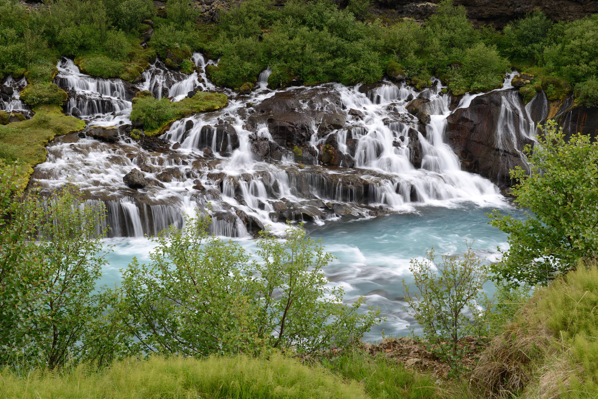Islandzki wodospad Hraunfossar z turkusowymi kaskadami.