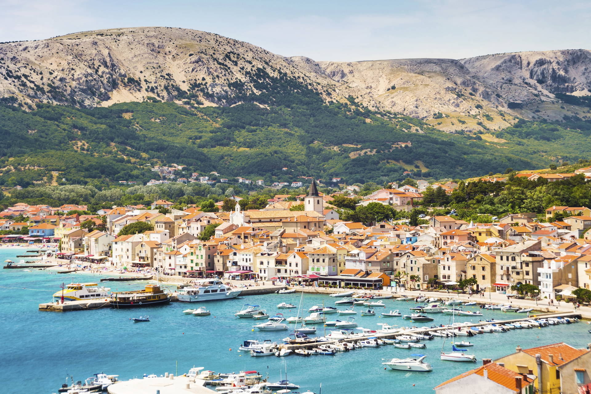 Miasto Baska w Chorwacji z portem jachtowym u podnóża gór.