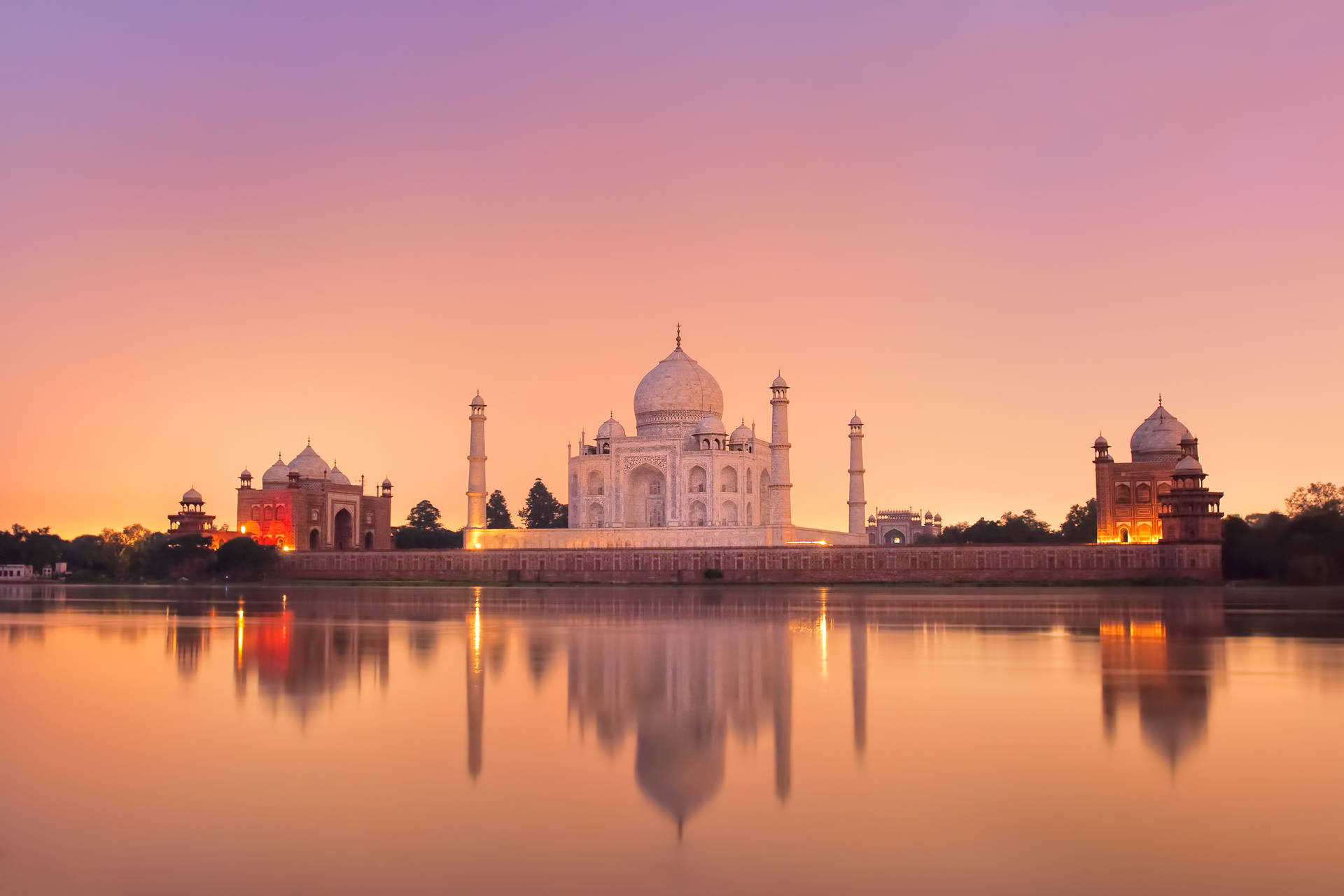 Taj Mahal odbija się w wodzie podczas zachodu słońca.