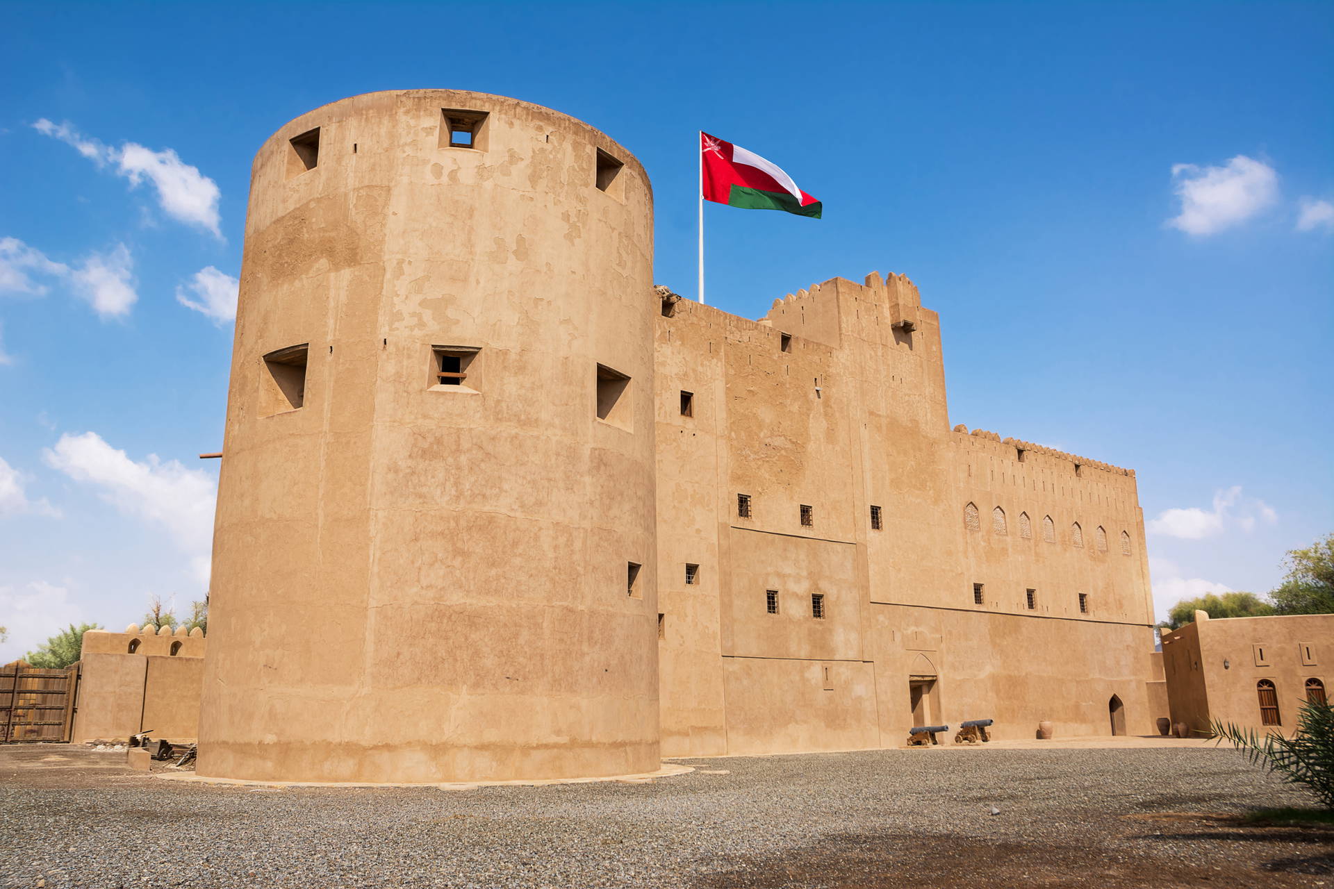 Fort Nizwa w Omanie z powiewającą flagą na tle błękitnego nieba.