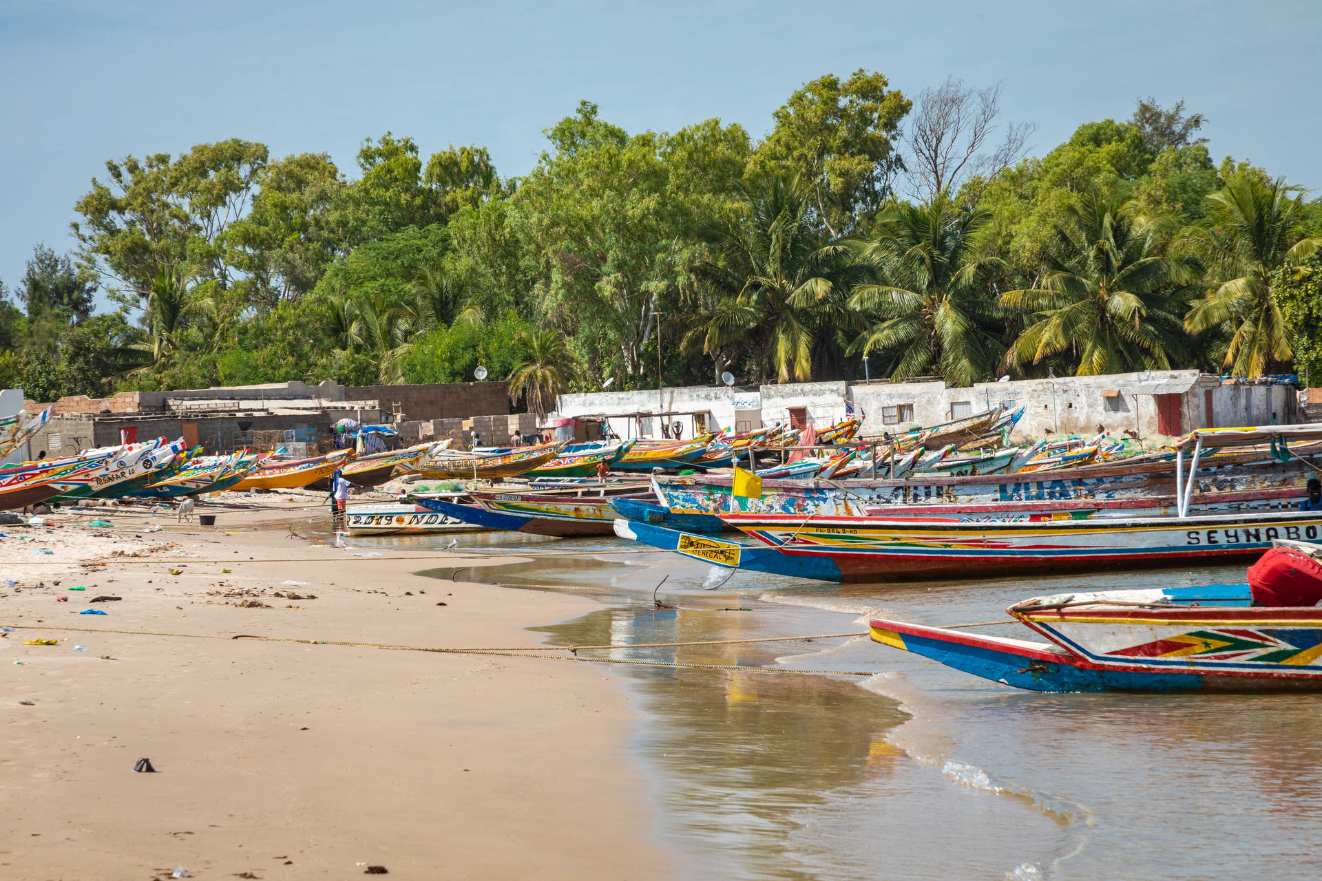 Kolorowe łodzie rybackie na piaszczystej plaży w Senegalu.