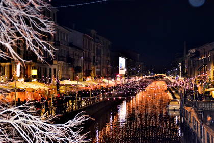 Nocny widok na oświetlony świątecznymi lampkami kanał Naviglio Grande w Mediolanie.