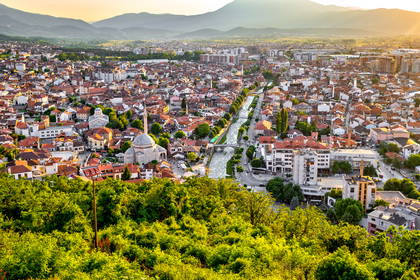 Panorama Prizrenu w Kosowie. Historyczne centrum miasta z rzeką i meczetem na tle gór.