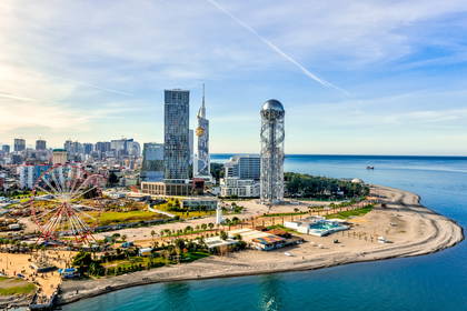 Panorama Batumi w Gruzji z wieżowcami, diabelskim młynem i plażą w tle.