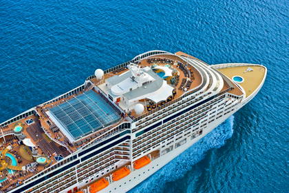 Ujęcie z góry statku wycieczkowego MSC Divina na błękitnym morzu. Na pokładach widać baseny i leżaki.