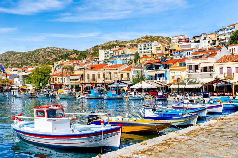 Kolorowe łodzie rybackie zacumowane w porcie Pythagoreion na Samos. W tle barwne domy miasteczka na wzgórzu.
