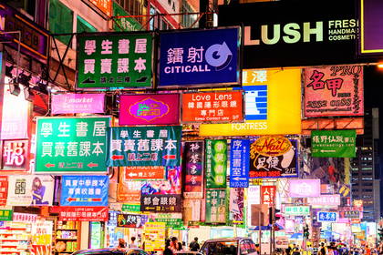 Ulica w Hongkongu nocą, oświetlona neonami. Widoczni piesi.